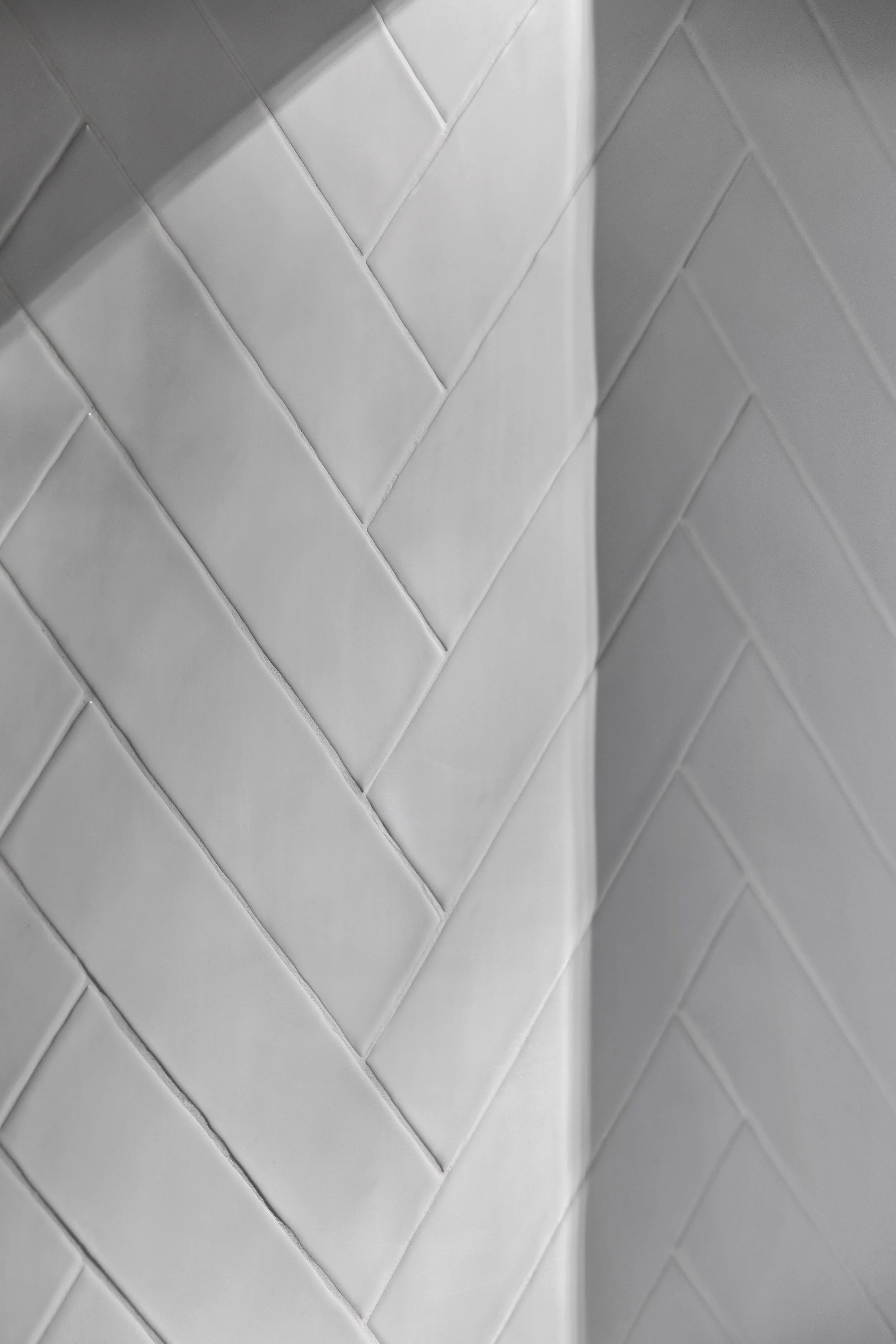Close-up photo of a white, quilted, padded wall with diagonal stitching.