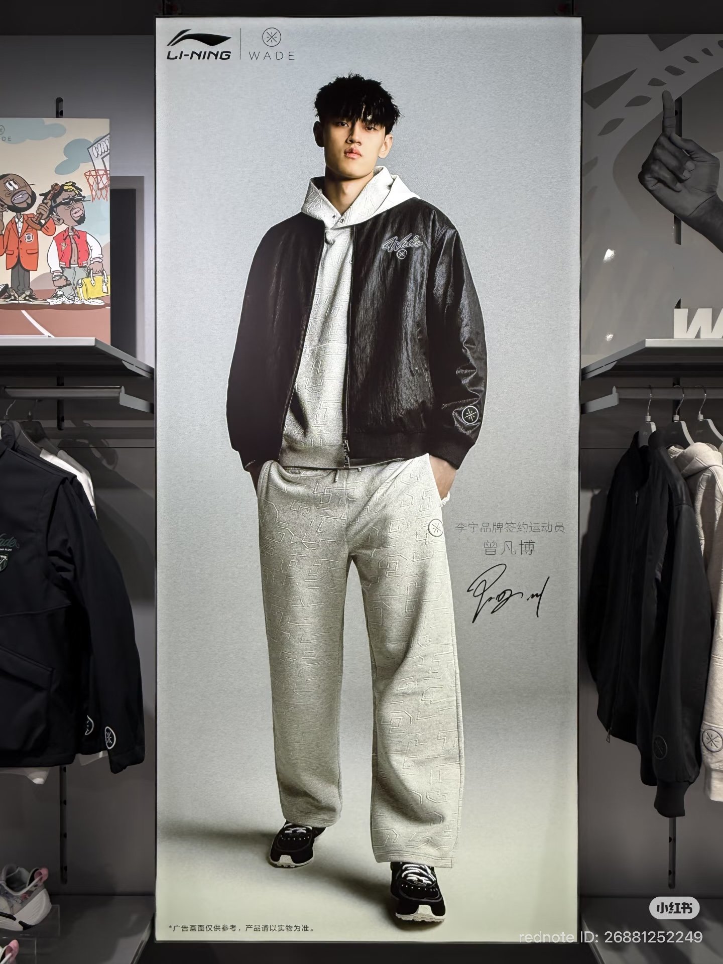 A fashion advertisement poster featuring a young male model in a black leather jacket, gray hoodie, and beige patterned sweatpants with hands in pockets, standing against a plain background with logos and signatures.