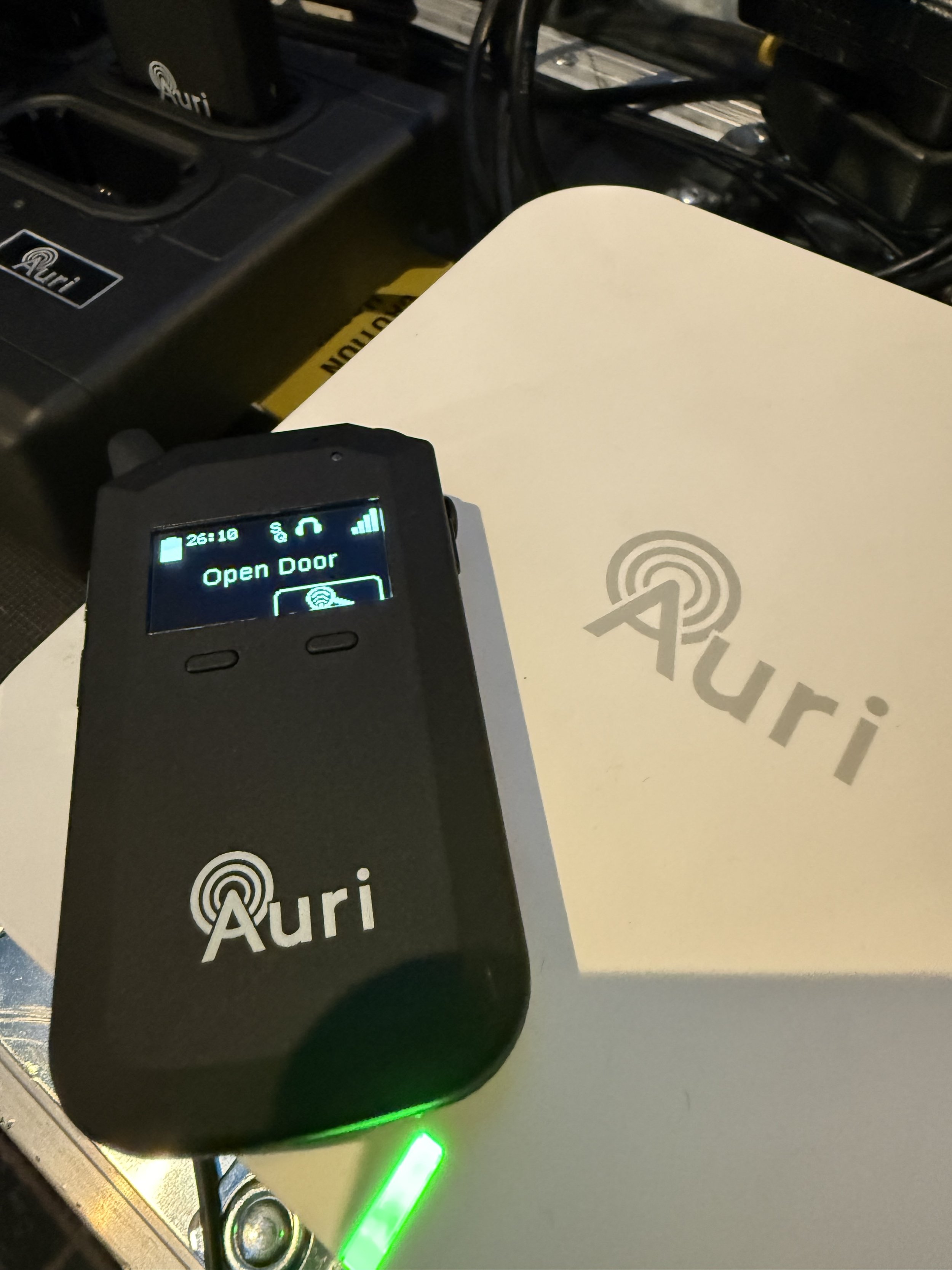 Close-up of an Auri wireless receiver situated on a larger Auri transmitter device with screws, cables, and electronic components visible in the background.