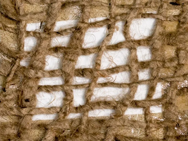 Close-up of brown rope tied in a grid pattern over a white surface.