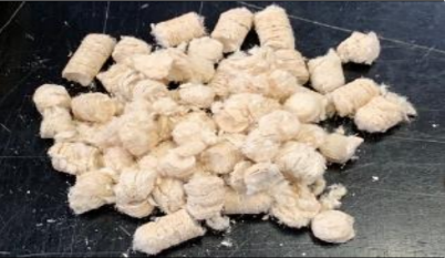 Pile of small, light-colored, fibrous objects on a dark surface.