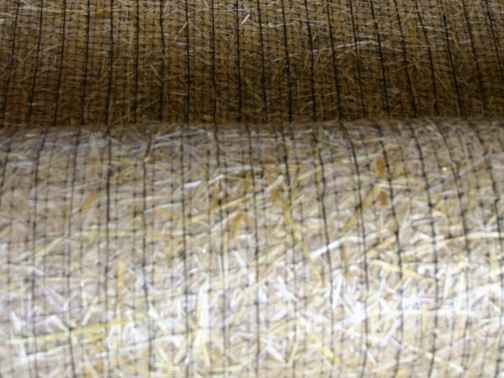 Bales of straw or hay stored stacked in a barn or shed.