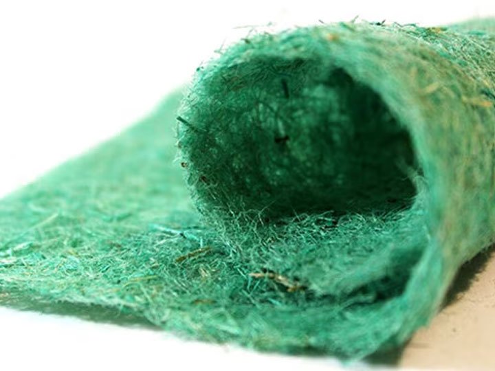 A close-up of a rolled-up green, fibrous textured mat or fabric.