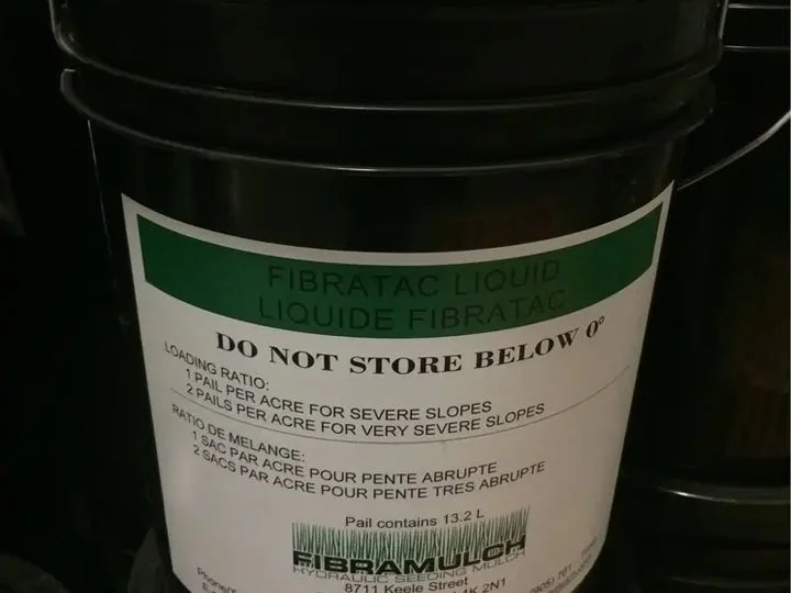 A black bucket with a label for Fibratac Liquid, a construction chemical, with instructions and warnings printed on it.