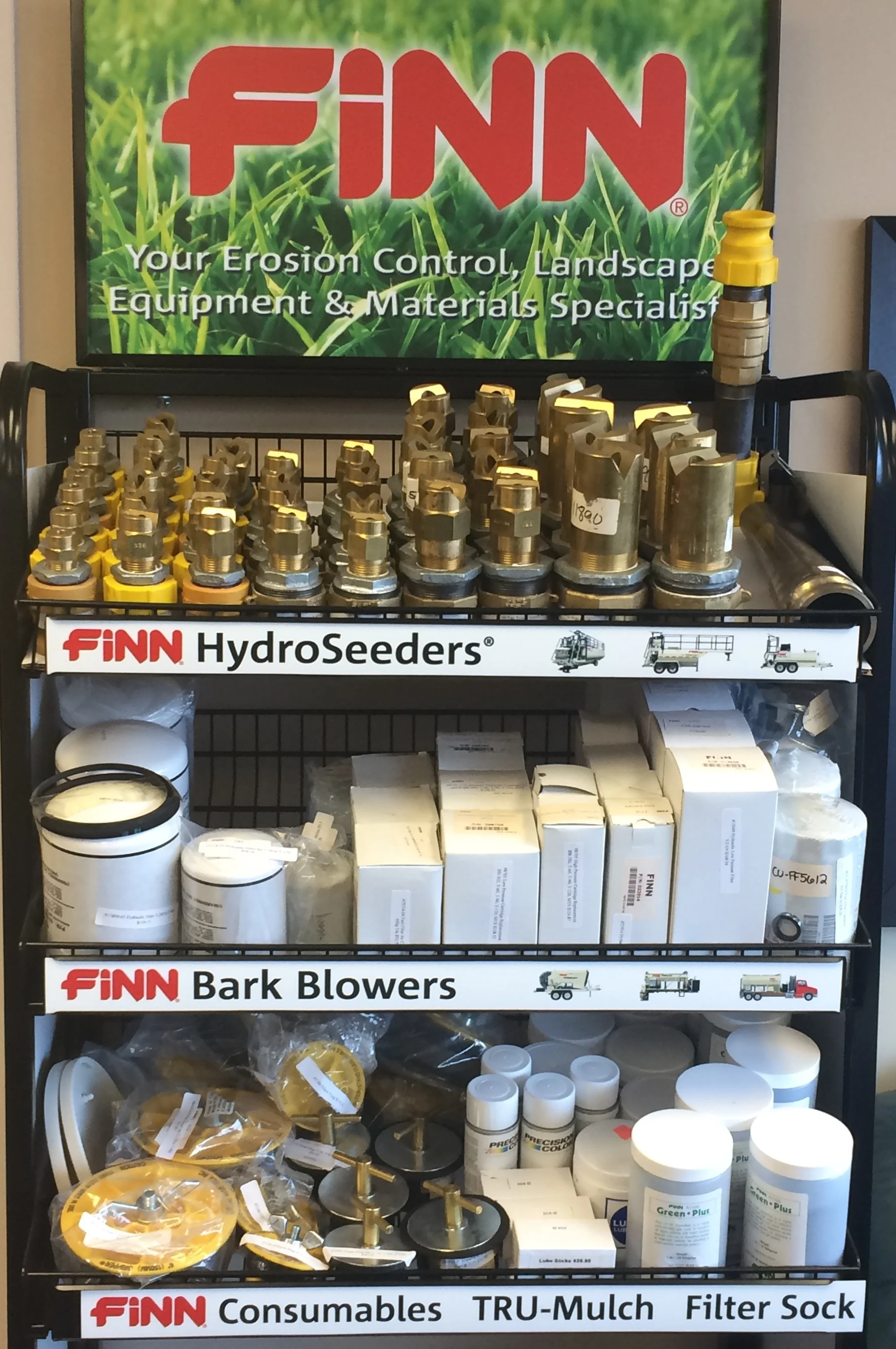 A display shelf with various landscaping supplies, including fittings, bark blowers, and filter socks, with a promotional sign for Finn landscaping products.