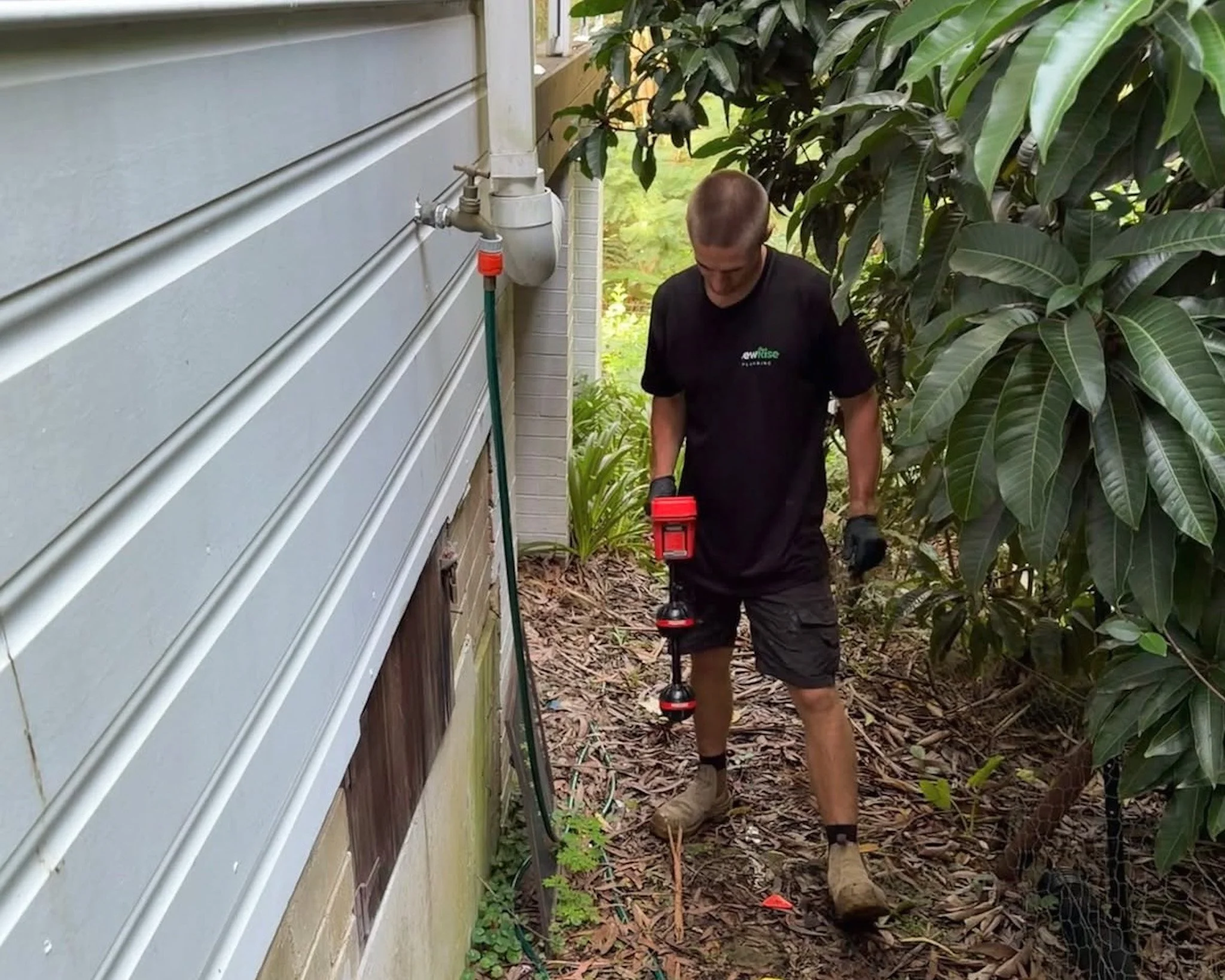 Jack from NewRise Plumbing using underground pipe locating equipment beside a residential property in Sydney