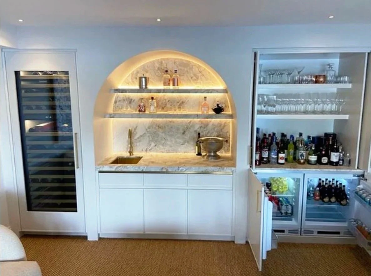 Custom home bar in Burraneer with backlit marble servery, brass tapware, bar sink, wine fridge and glass-front drinks fridges.