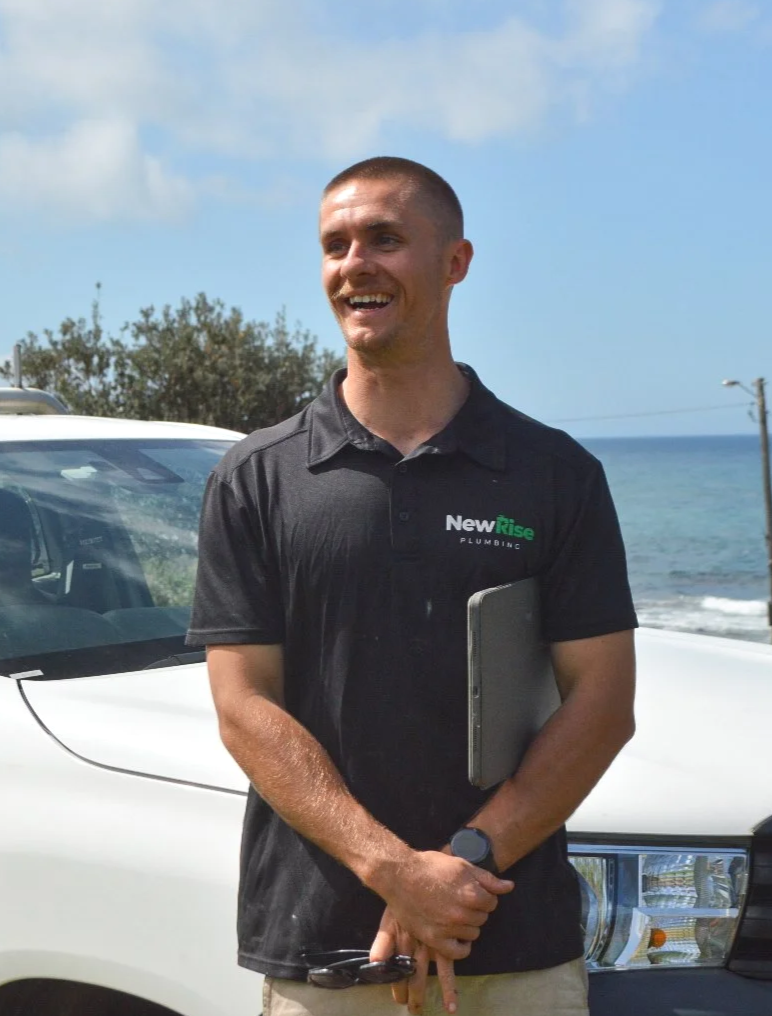 Jack, founder of NewRise Plumbing, holding a laptop beside his plumbing ute in Sydney