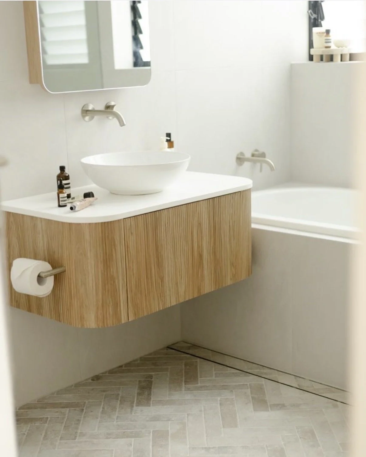 Coastal bathroom renovation in Coogee with wall-mounted tapware, vessel basin, mirrored cabinetry and soft neutral finishes.