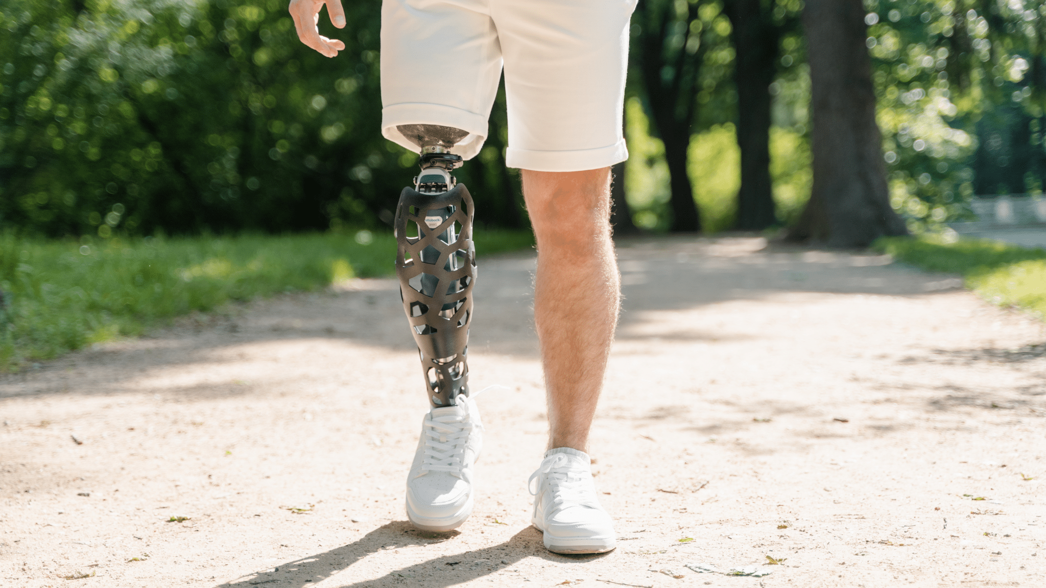 Person with a prosthetic leg walking on a park trail.