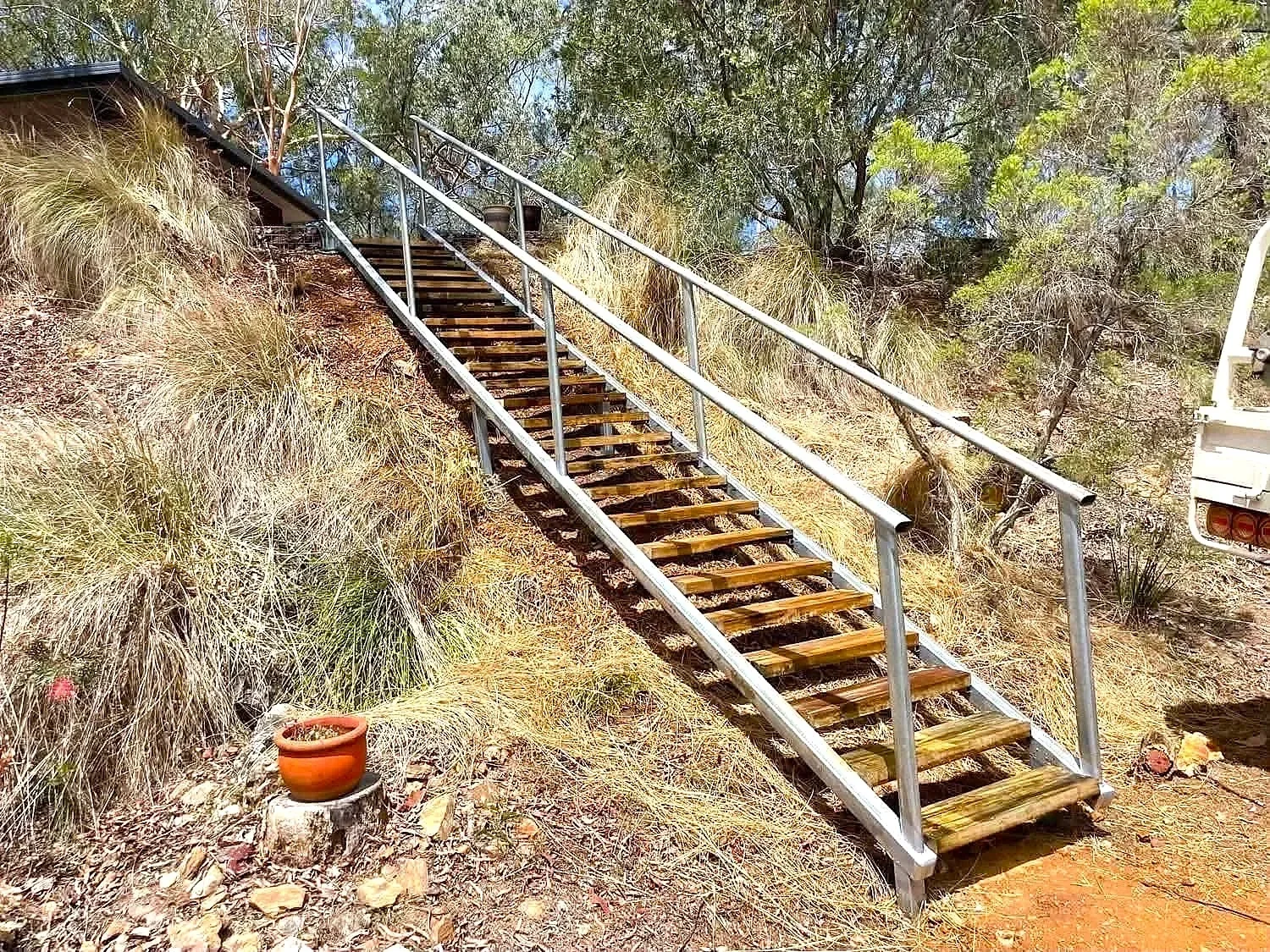 Outdoor timber staircase with steel handrails on a sloping rural property in the Atherton Tablelands