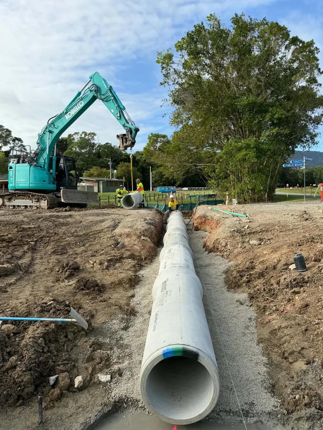 Excavator assisting with large pipe installation and trench works in the Daintree, Far North Queensland.