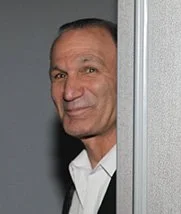 Man peeking out from behind a wall, smiling
