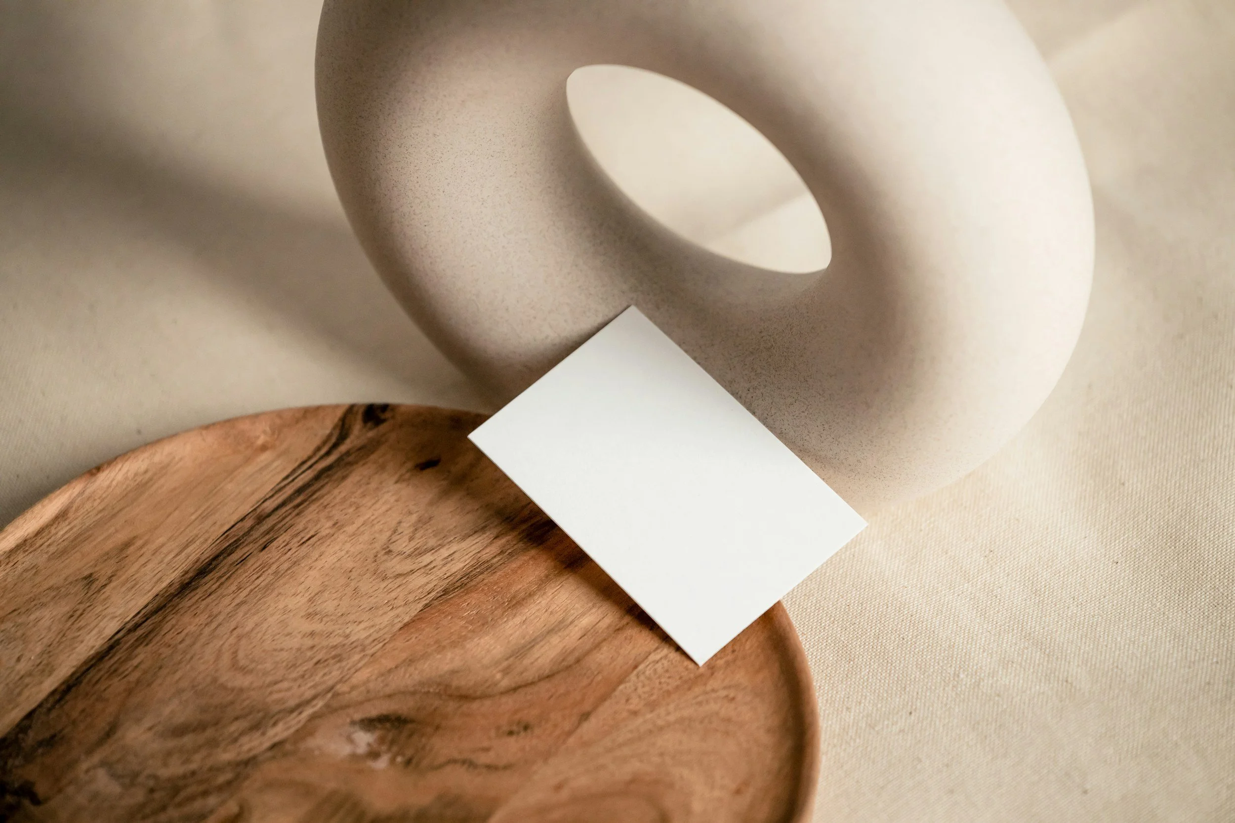 Close-up of a wooden bowl and a piece of beige paper resting on a beige fabric background.