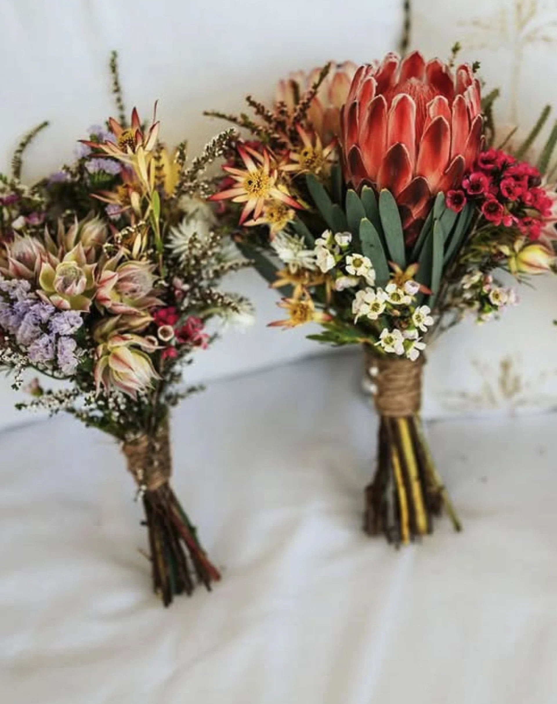 Two small flower bouquets with various colorful flowers and greenery, tied with twine.