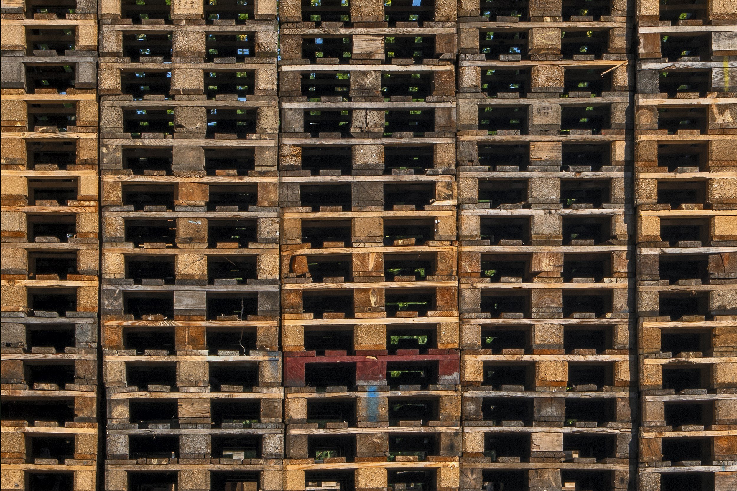 Stacks of wooden pallets arranged in a grid pattern with visible open spaces between layers.