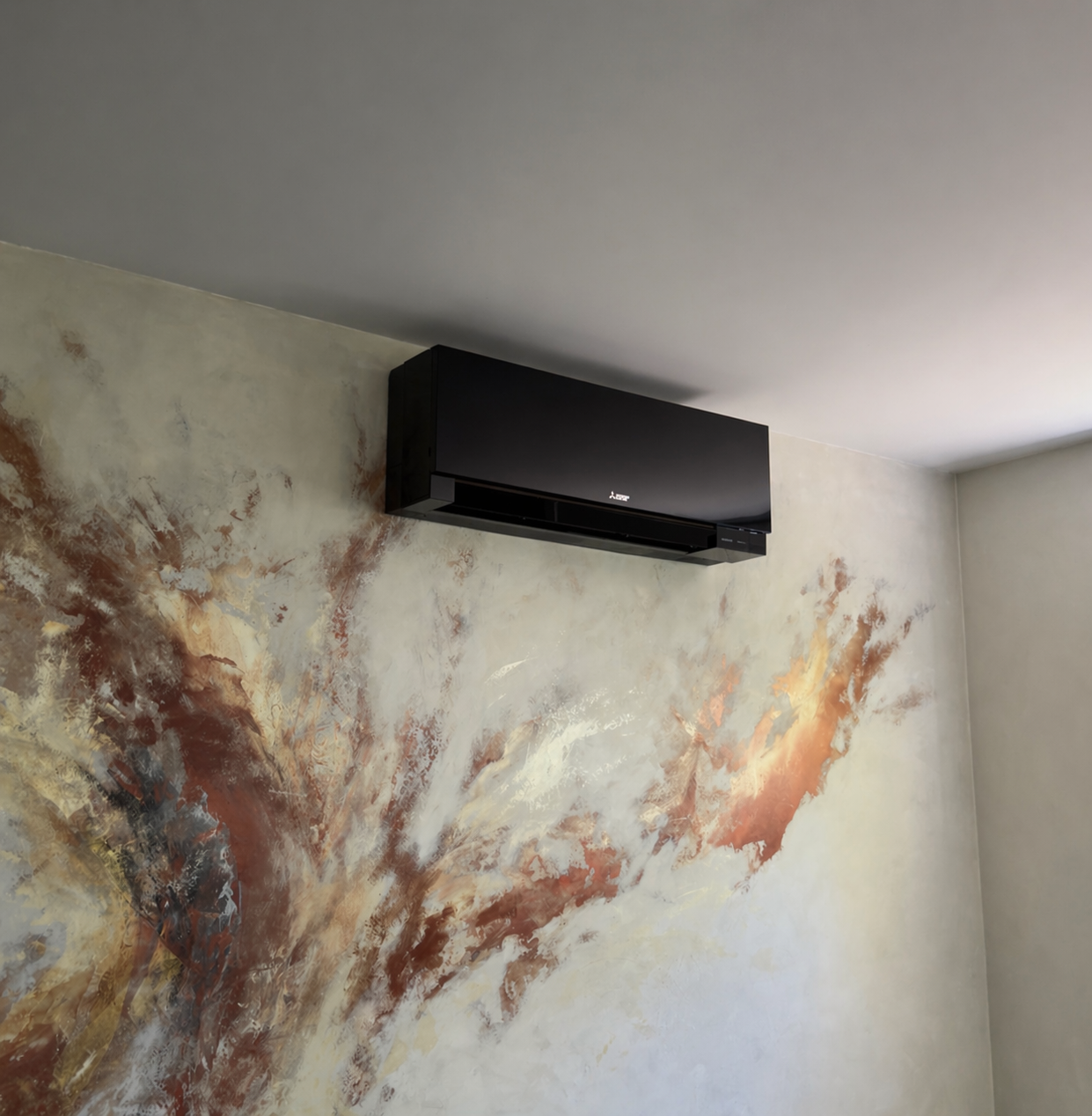 Black split air conditioner mounted on a wall above a colorful abstract mural in a room.