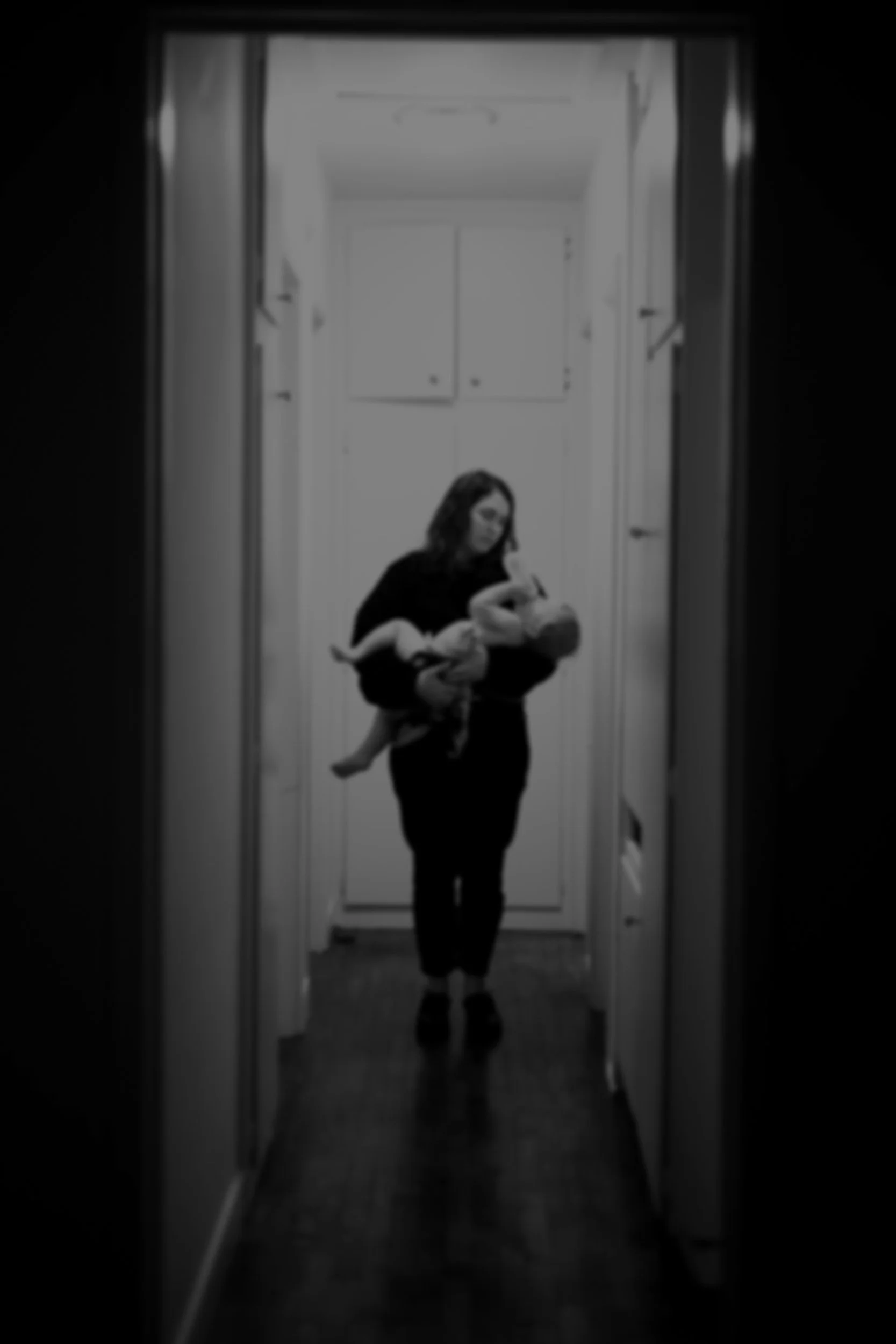A mother holding her child, slightly overwhelmed but acknowledging motherhood.