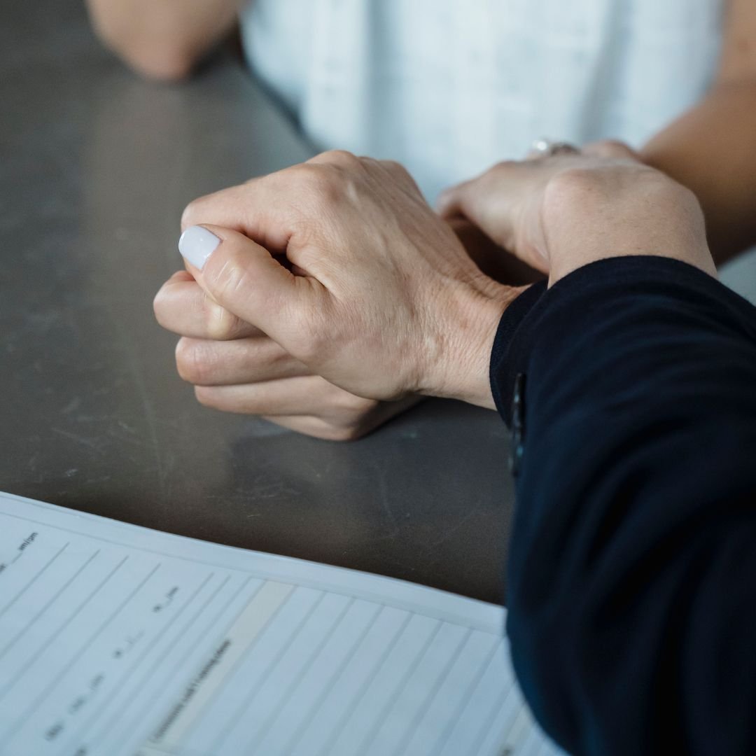 Two people holding hands on a table with a notebook nearby.