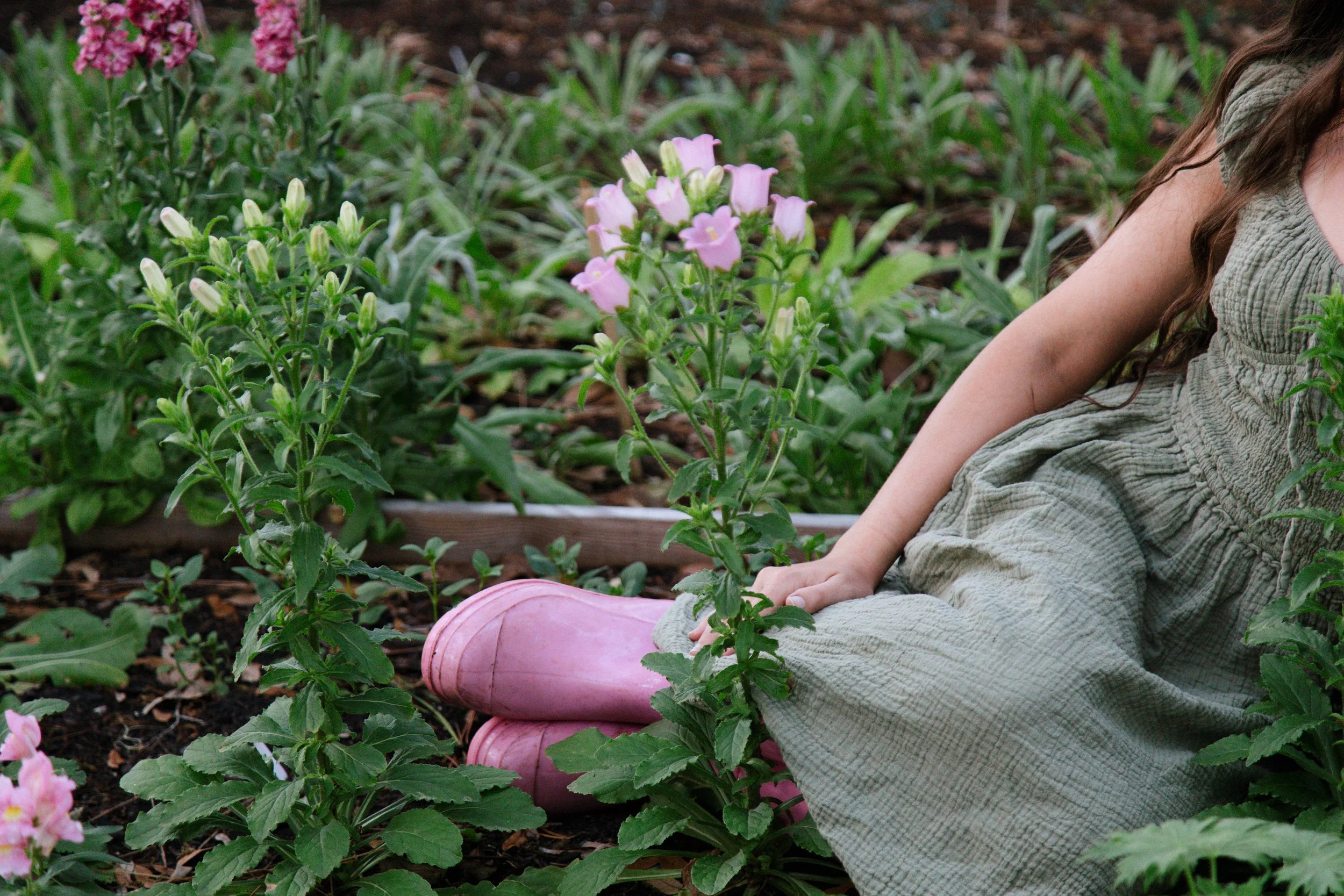 Sitting in the garden with pink campanula and boots