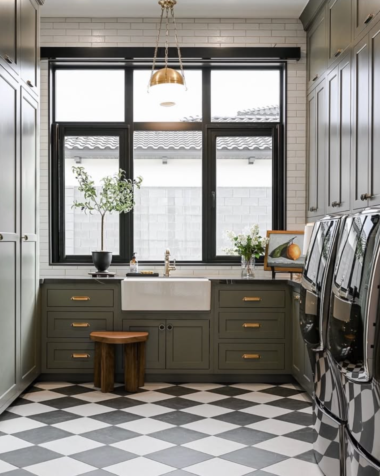 Castle Pines laundry room with green cabinetry, farmhouse sink, and checkered tile floor.