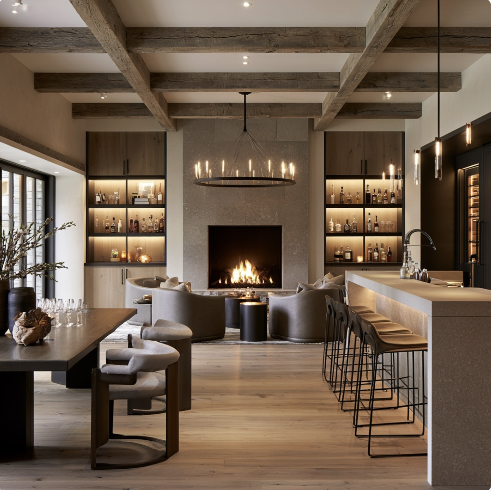 Luxury walk out basement bar and lounge with stone fireplace, custom backlit bar shelving, and rustic wood beam ceiling.  Interior design by Indigo Day Designs, an interior design and renovation studio serving Castle Rock and Castle Pines, Colorado.