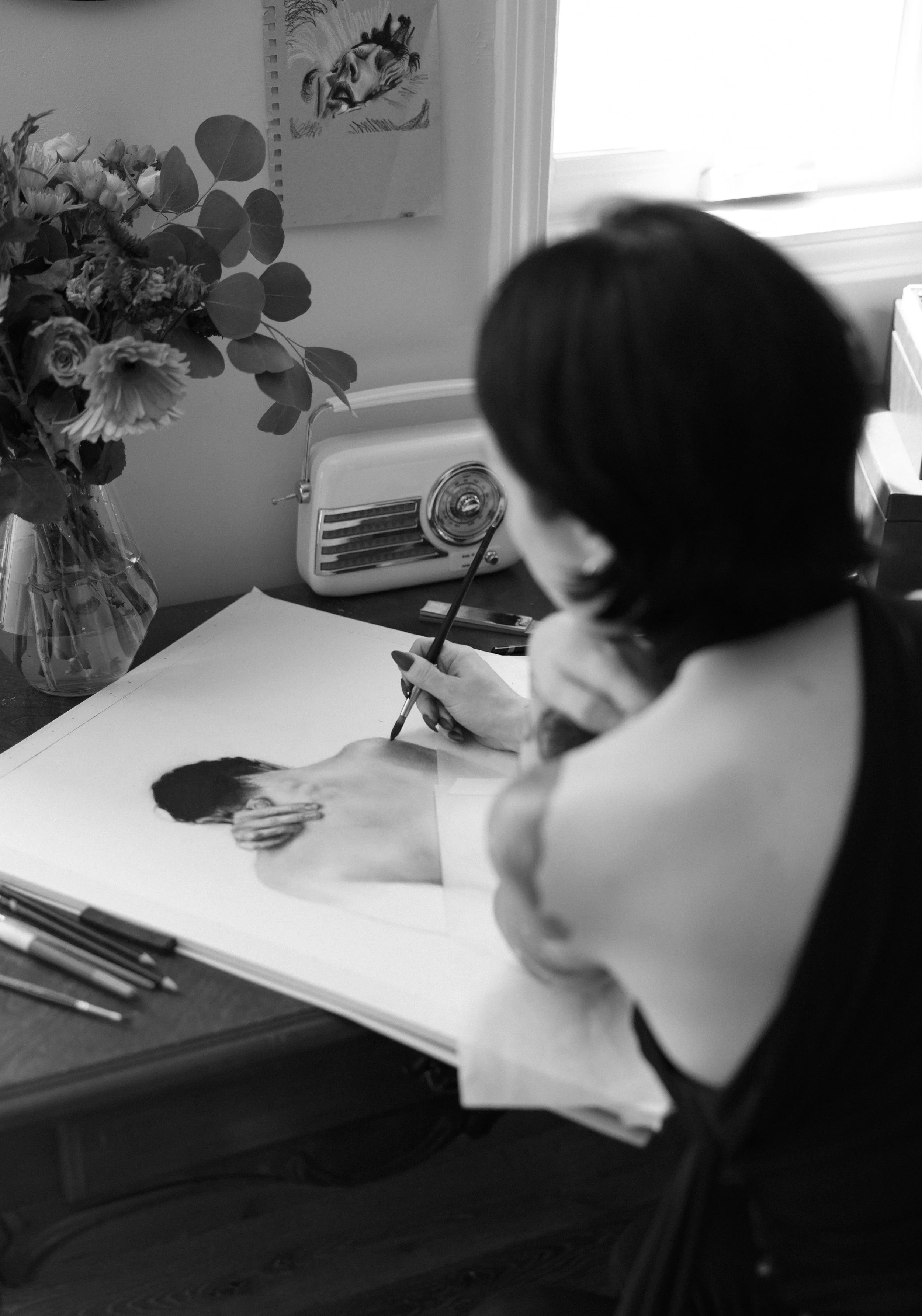 Abby Thiede drawing a charcoal portrait at her desk