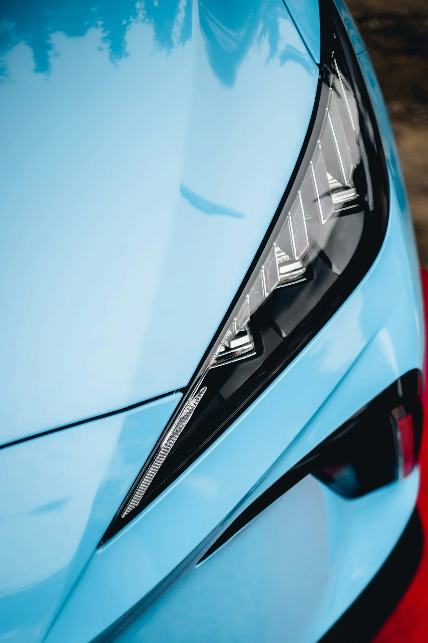 Blue supercar headlight close-up with high-gloss finish after professional automotive detailing
