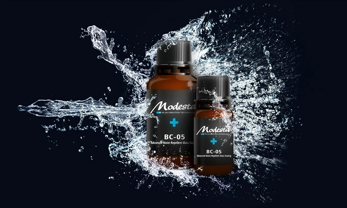 Two bottles of Modesta BC-05 water-repellent glass coating with water splashing around them.