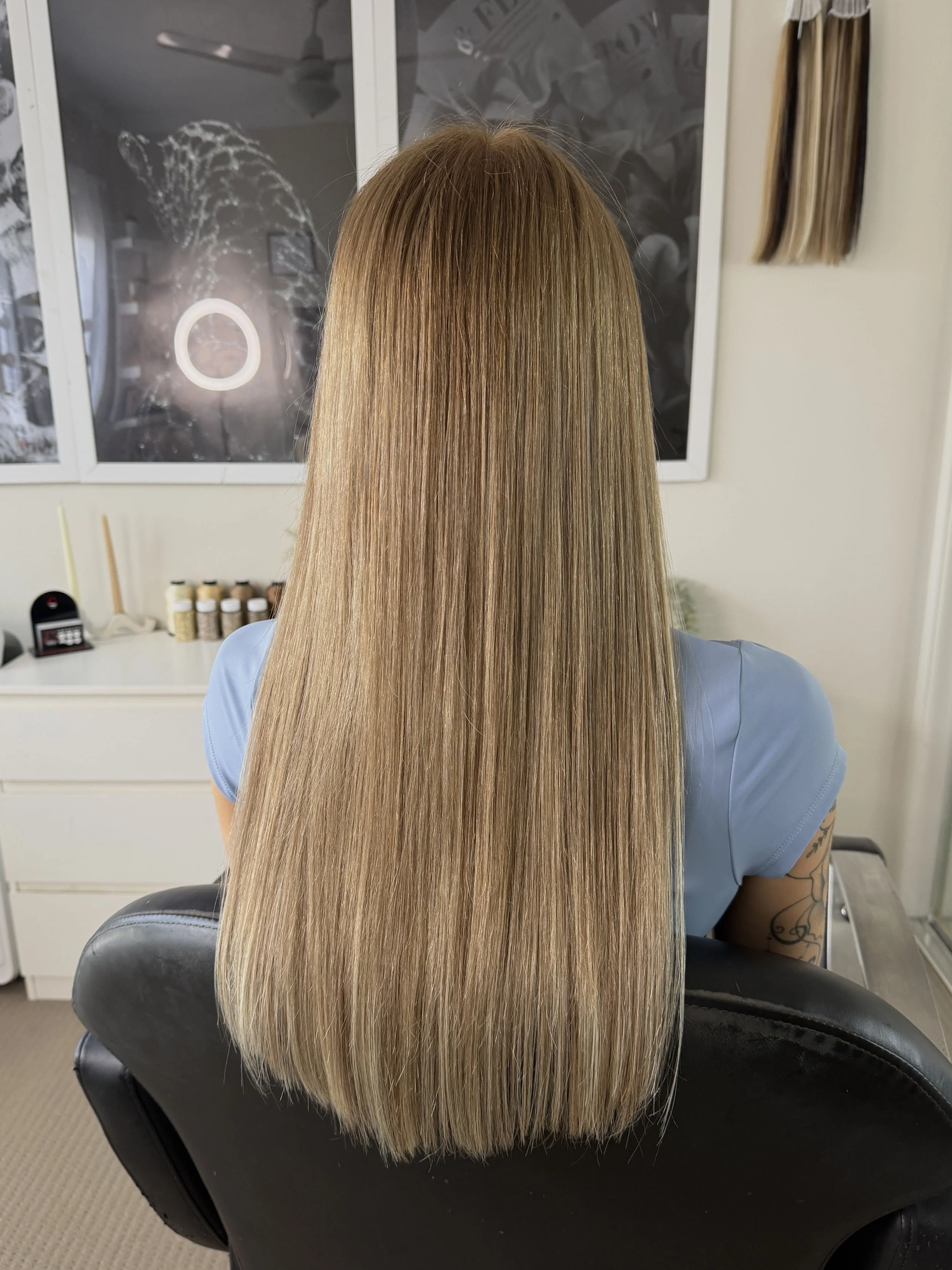 Long, straight blonde dimensional hair extensions, seamlessly blended for a flawless, naturally elevated finish.