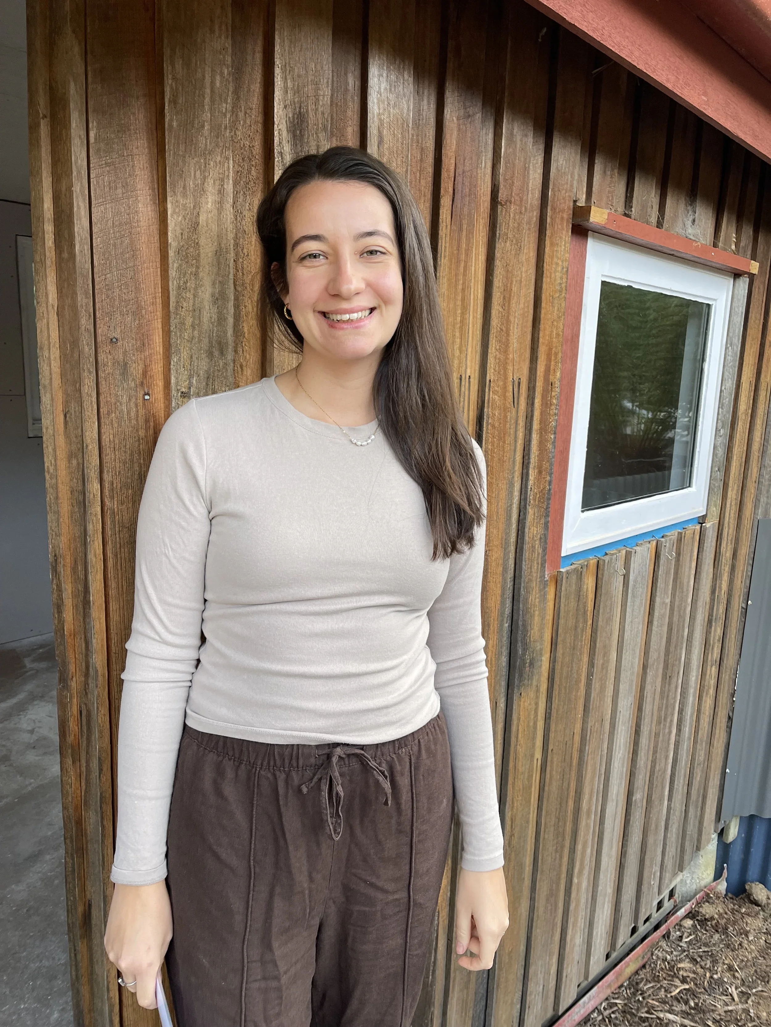 Justine the practitioner in front of a wooden home.