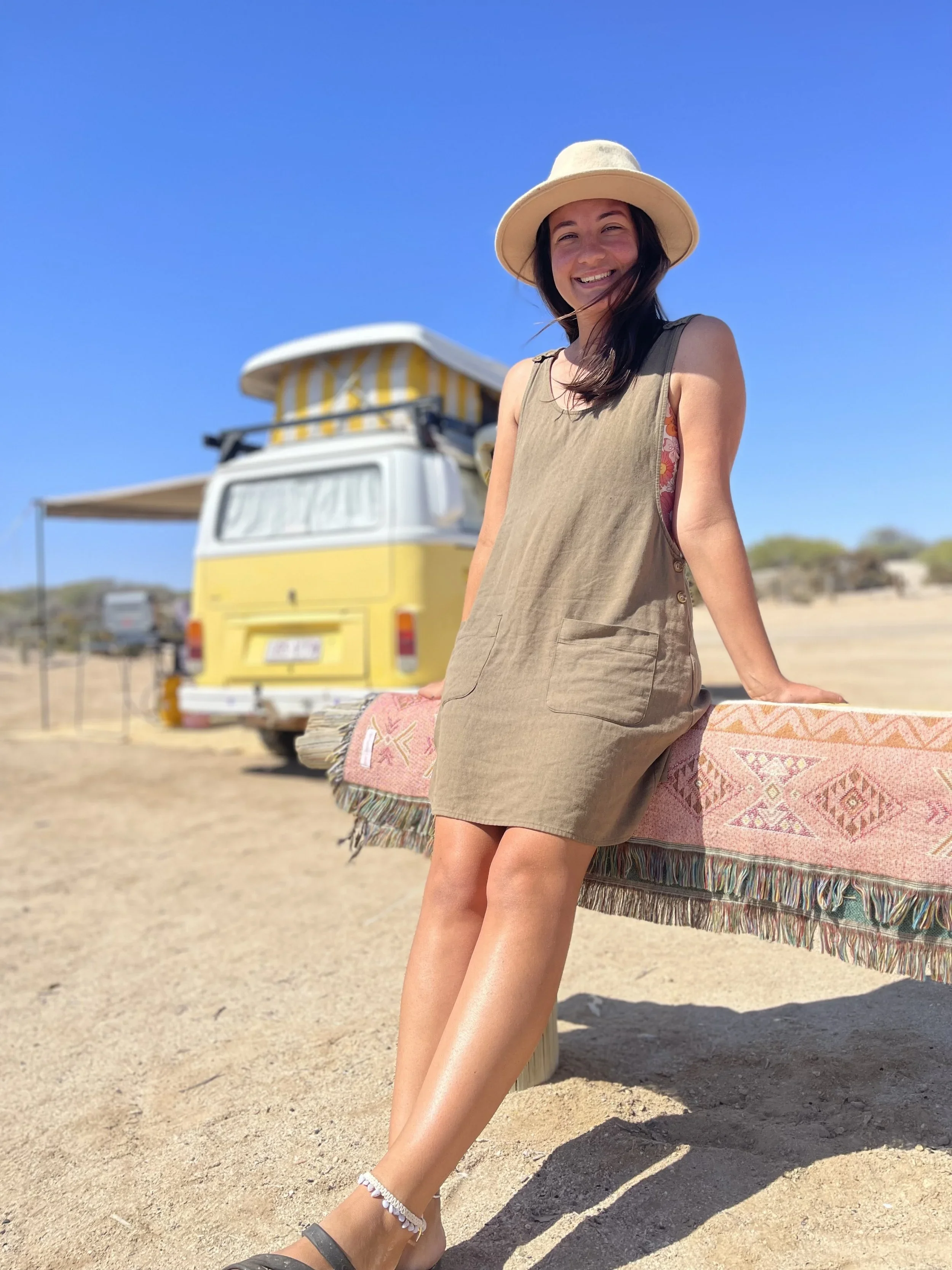 Justine, the practitioner, in front of yellow van enjoying nature wearing a yellow bucket hat.