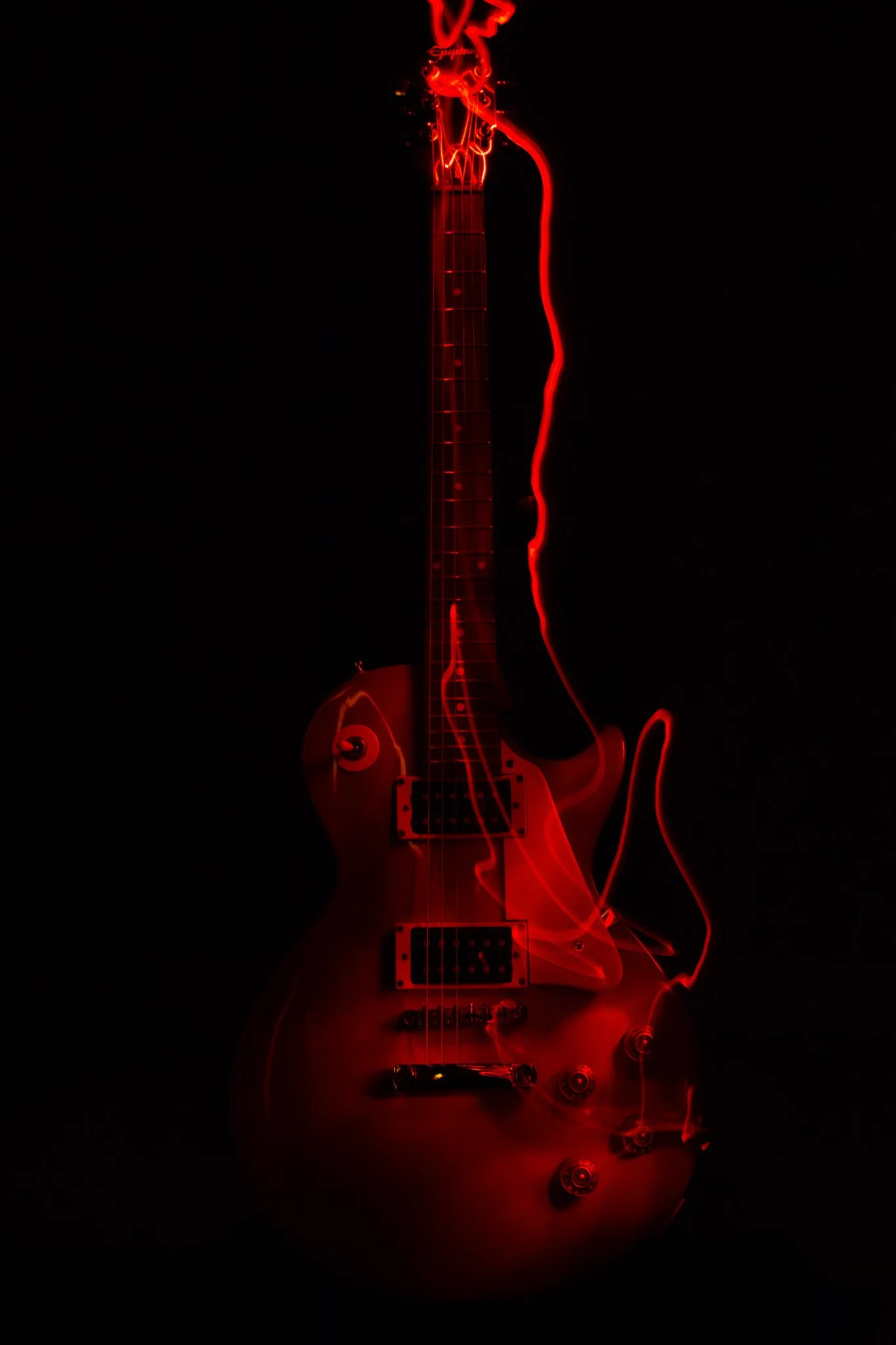 Electric guitar with red neon light effects against a black background.