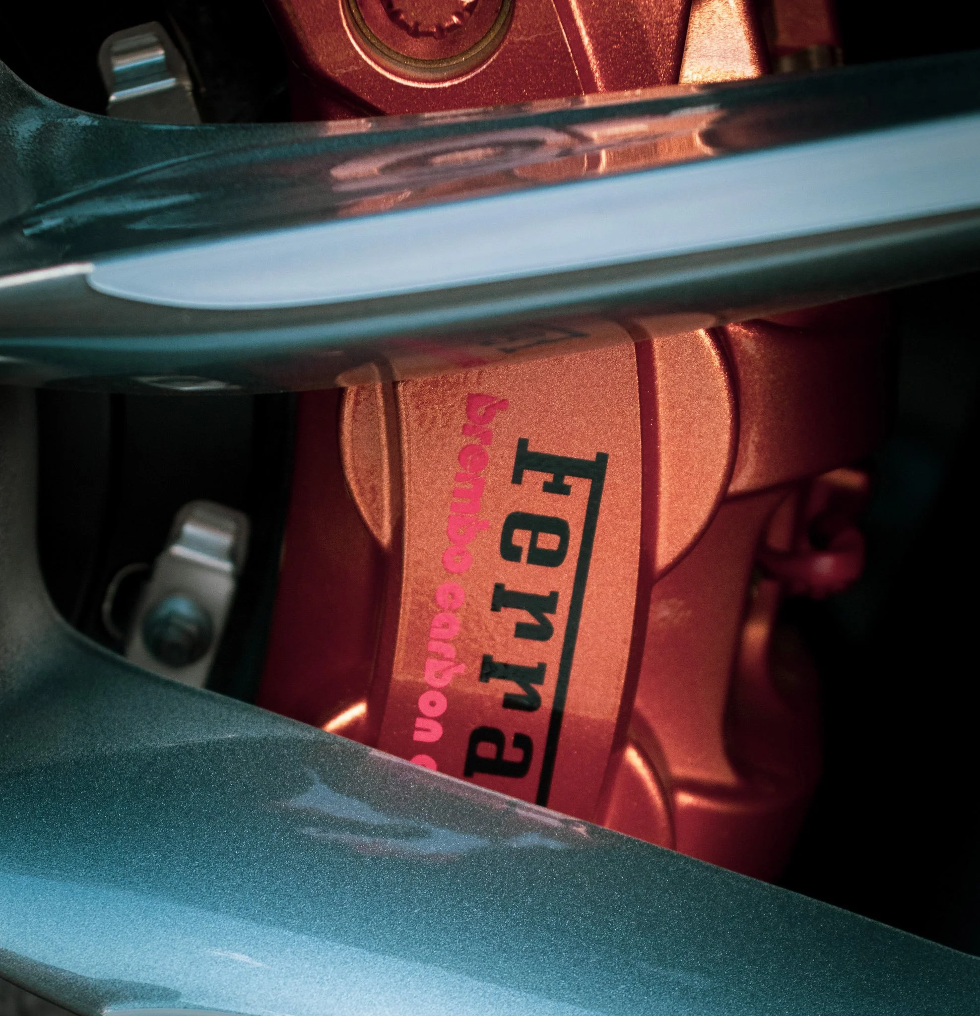 Close-up of a red object with black text, placed on a teal surface, with parts of a black and gray object visible in the background.