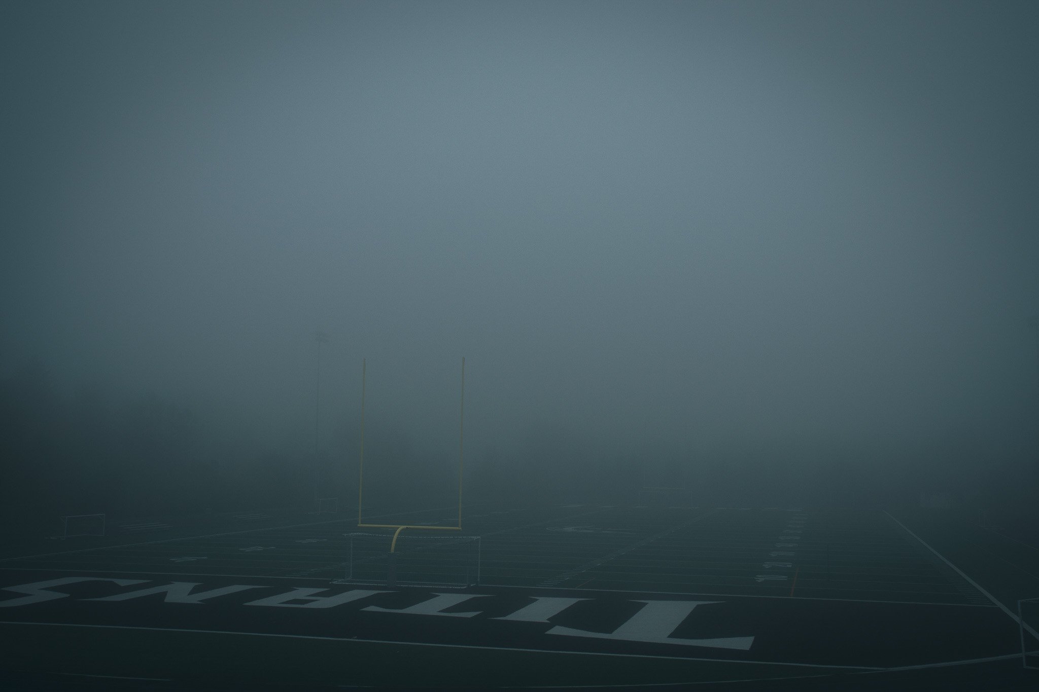 A foggy football stadium with goalposts and field markings visible.