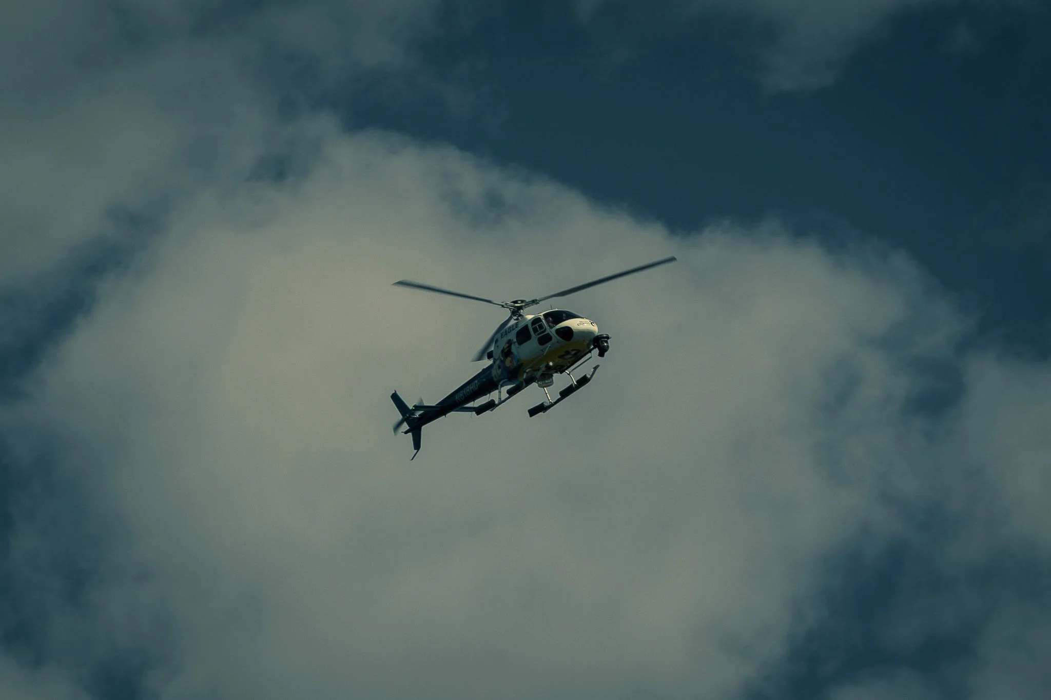 A helicopter flying in the sky with clouds in the background.