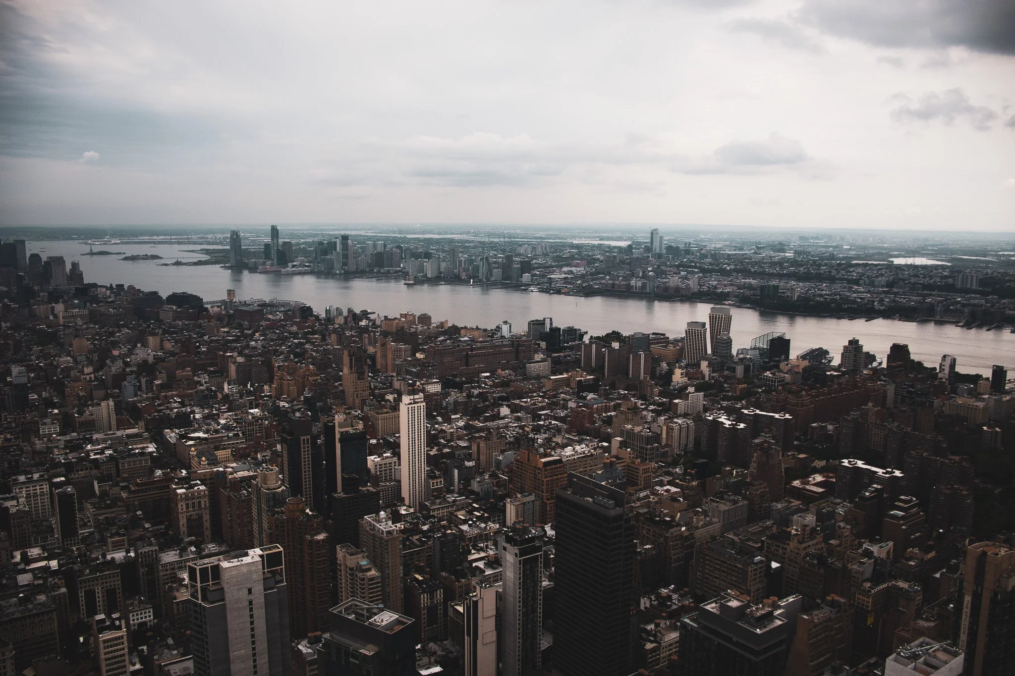 A cityscape view from a high vantage point, showing tall skyscrapers, a river, and overcast sky.