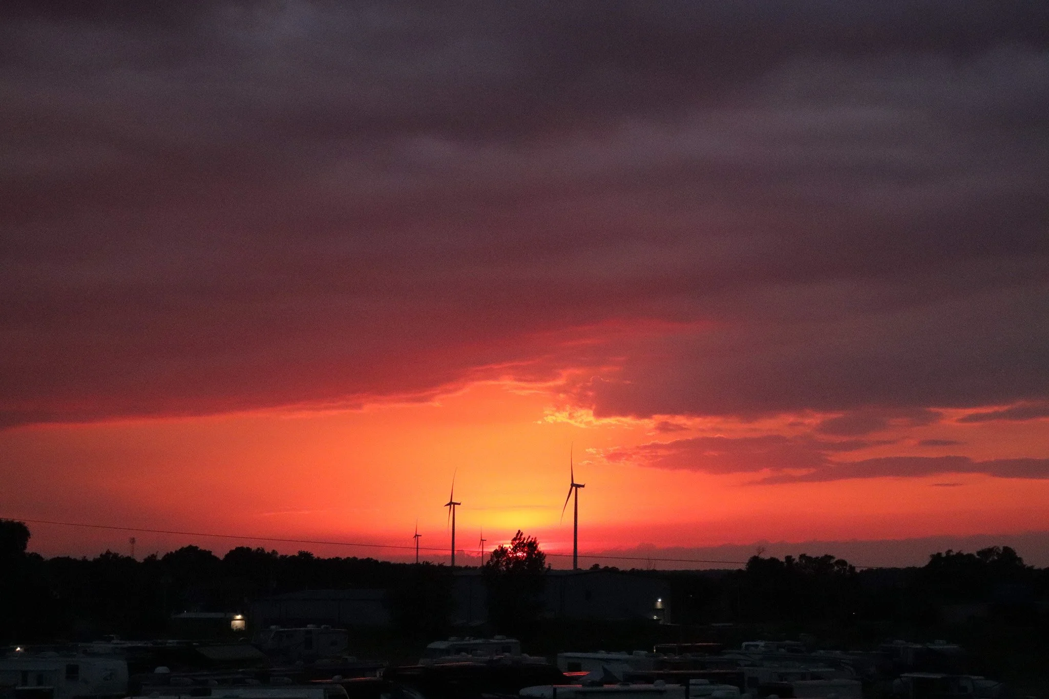 Sunset with dark clouds and wind turbines on the horizon