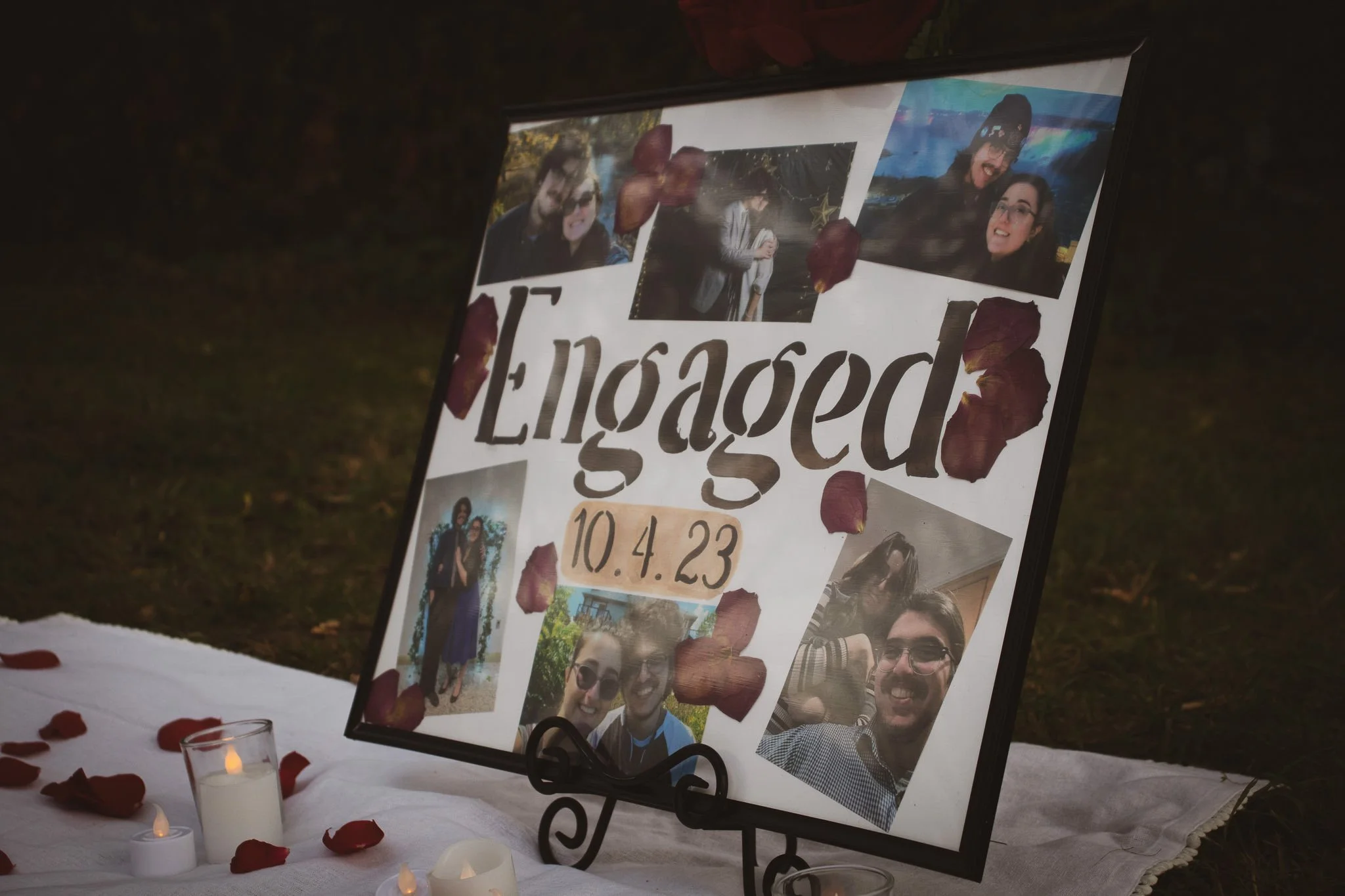 Memorial display with a collage of photographs, candles, and red rose petals for a person named Logan, with the date 10.4.23.