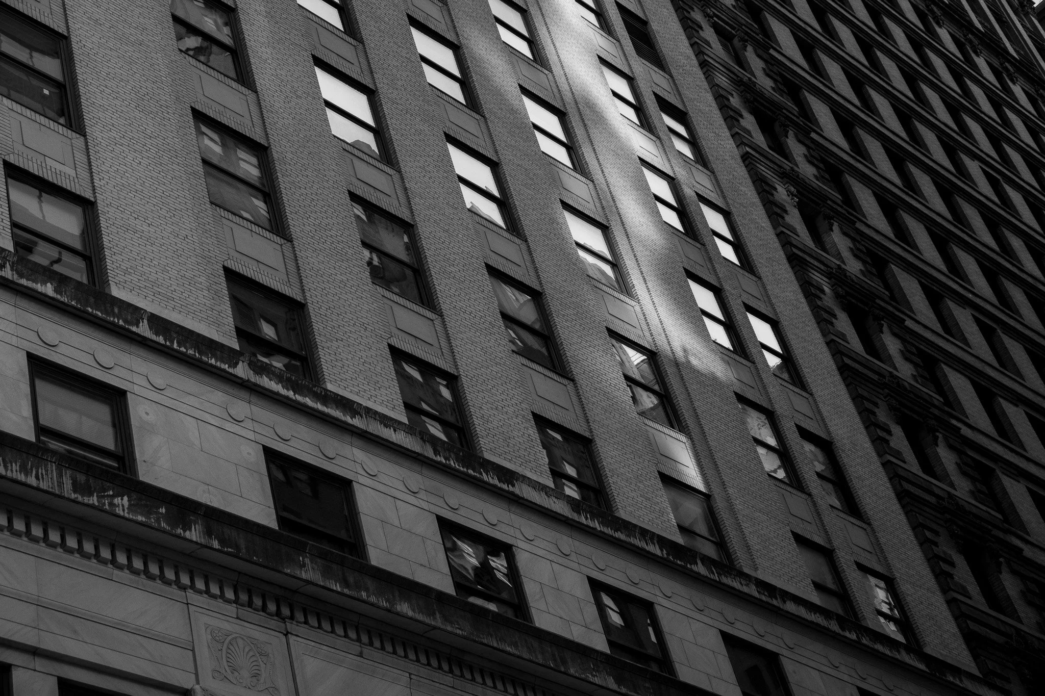 Black and white photo of a skyscraper with multiple windows and architectural details.