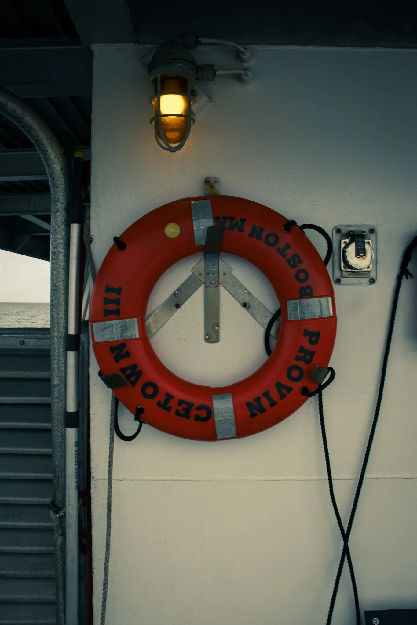 A life preserver hanging on a wall with a light above it.