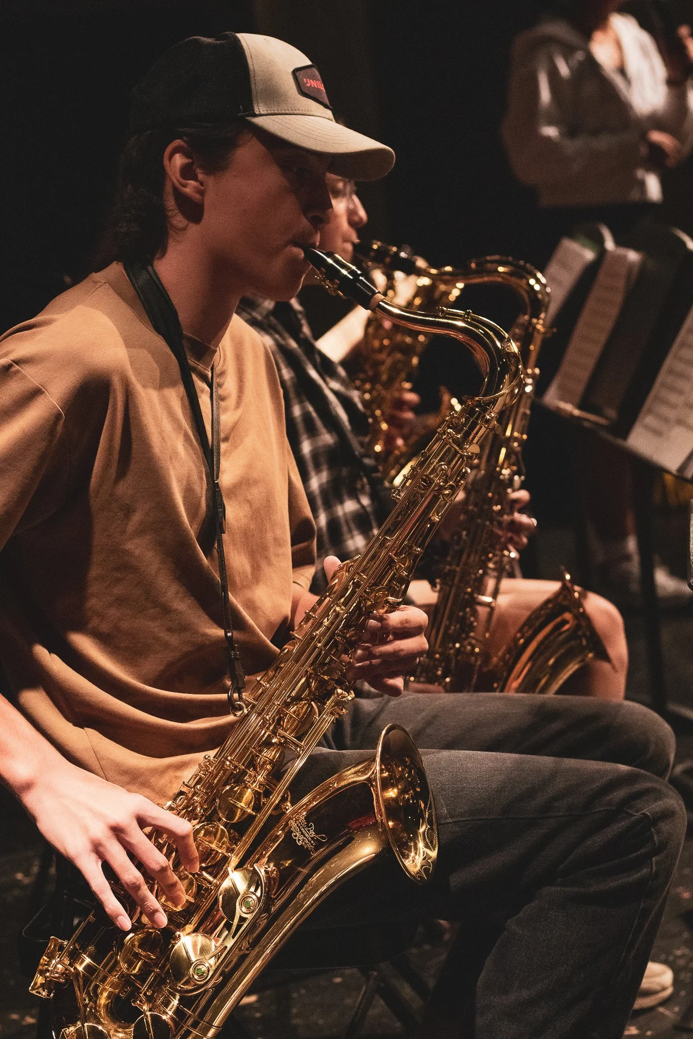 People playing saxophones in a band during a performance.