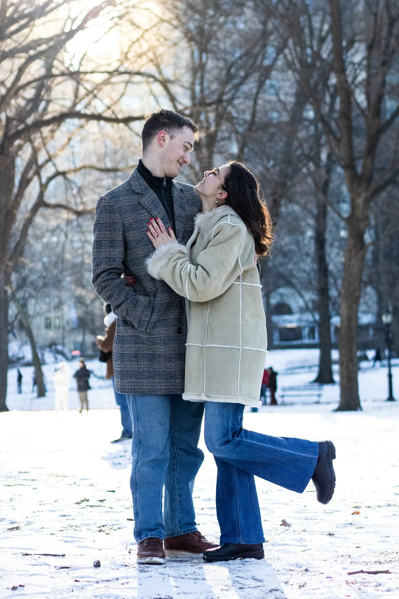 A couple in winter clothing sharing a moment in a park snowy landscape.