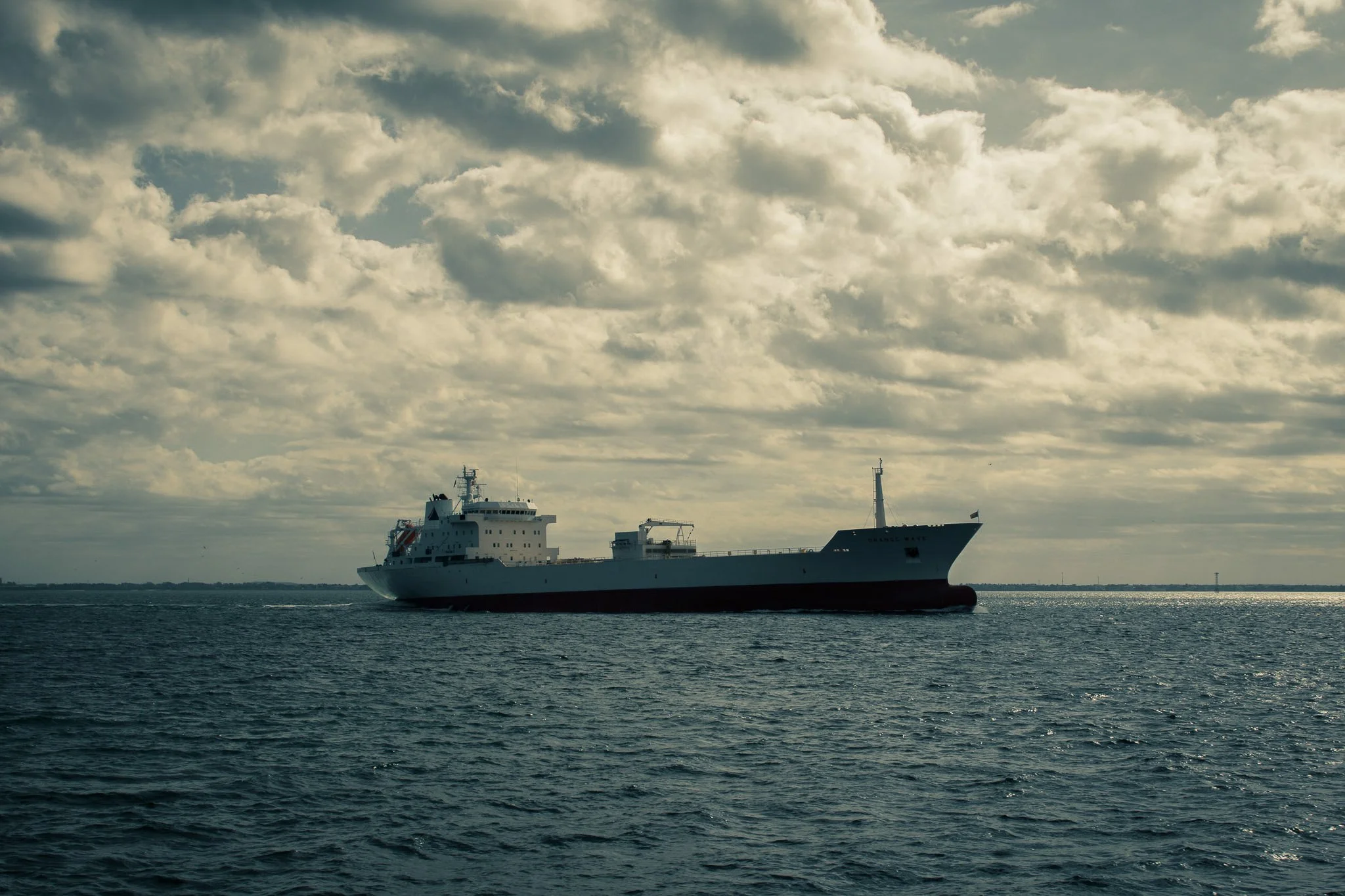 A large white ship sailing on the water under a cloudy sky.