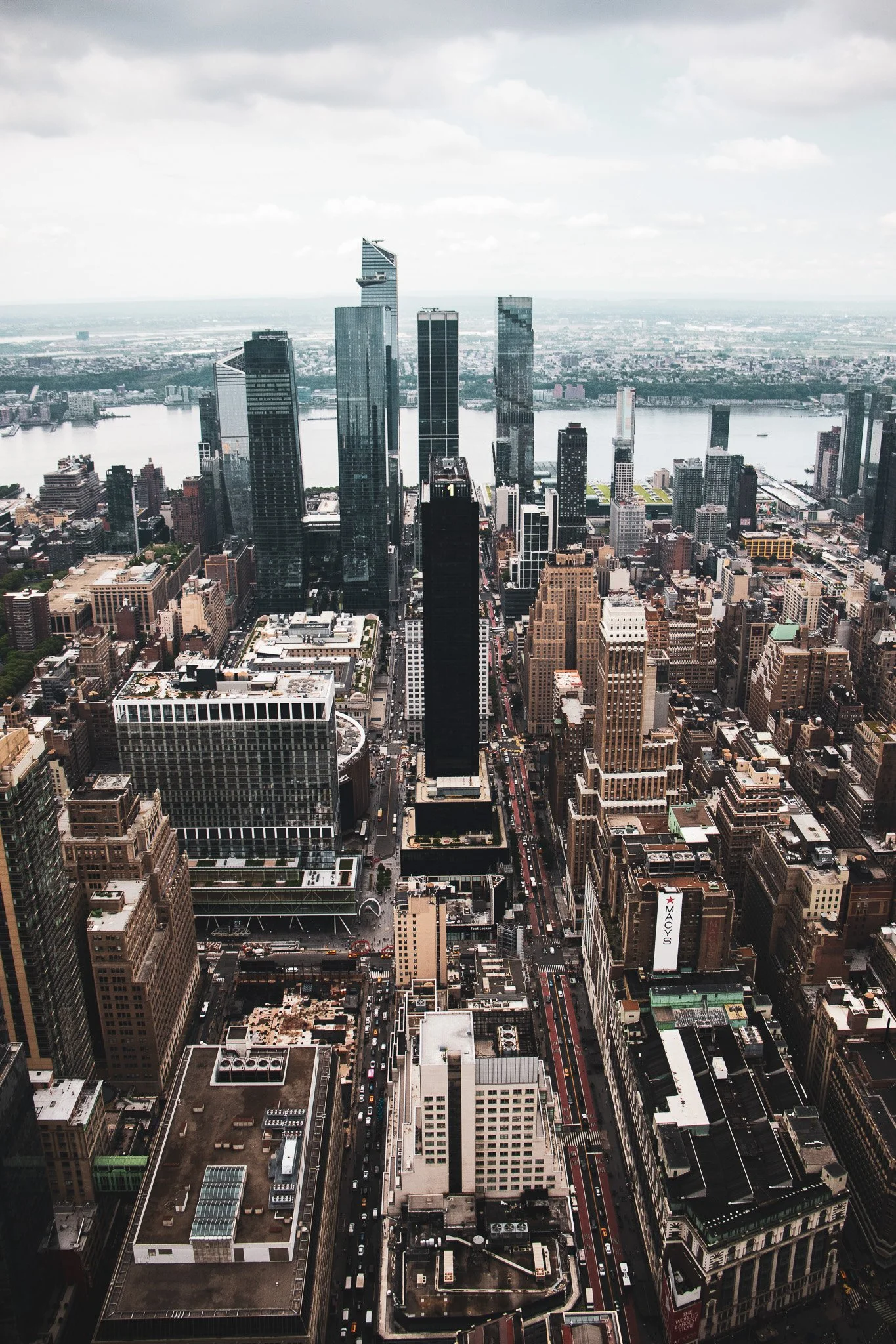 An aerial view of a city skyline featuring tall skyscrapers, a river in the background, and busy streets below.