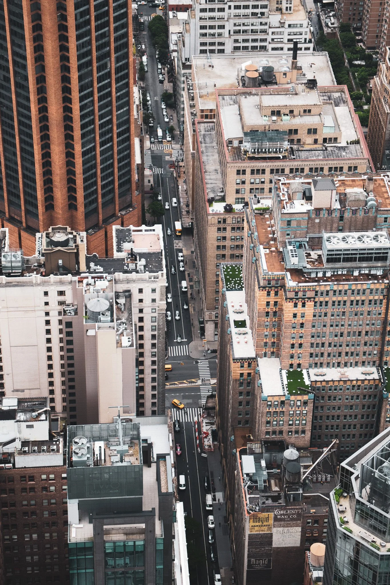 Aerial view of a city with tall office buildings and streets filled with cars and pedestrians.