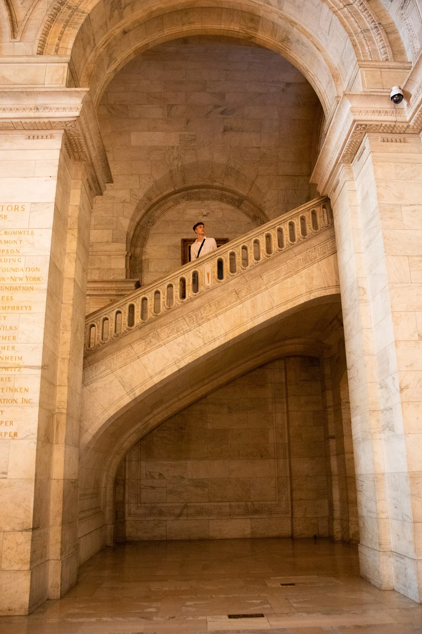 A person standing on a marble staircase inside a grand, historic building with arched ceilings and ornate architectural details.