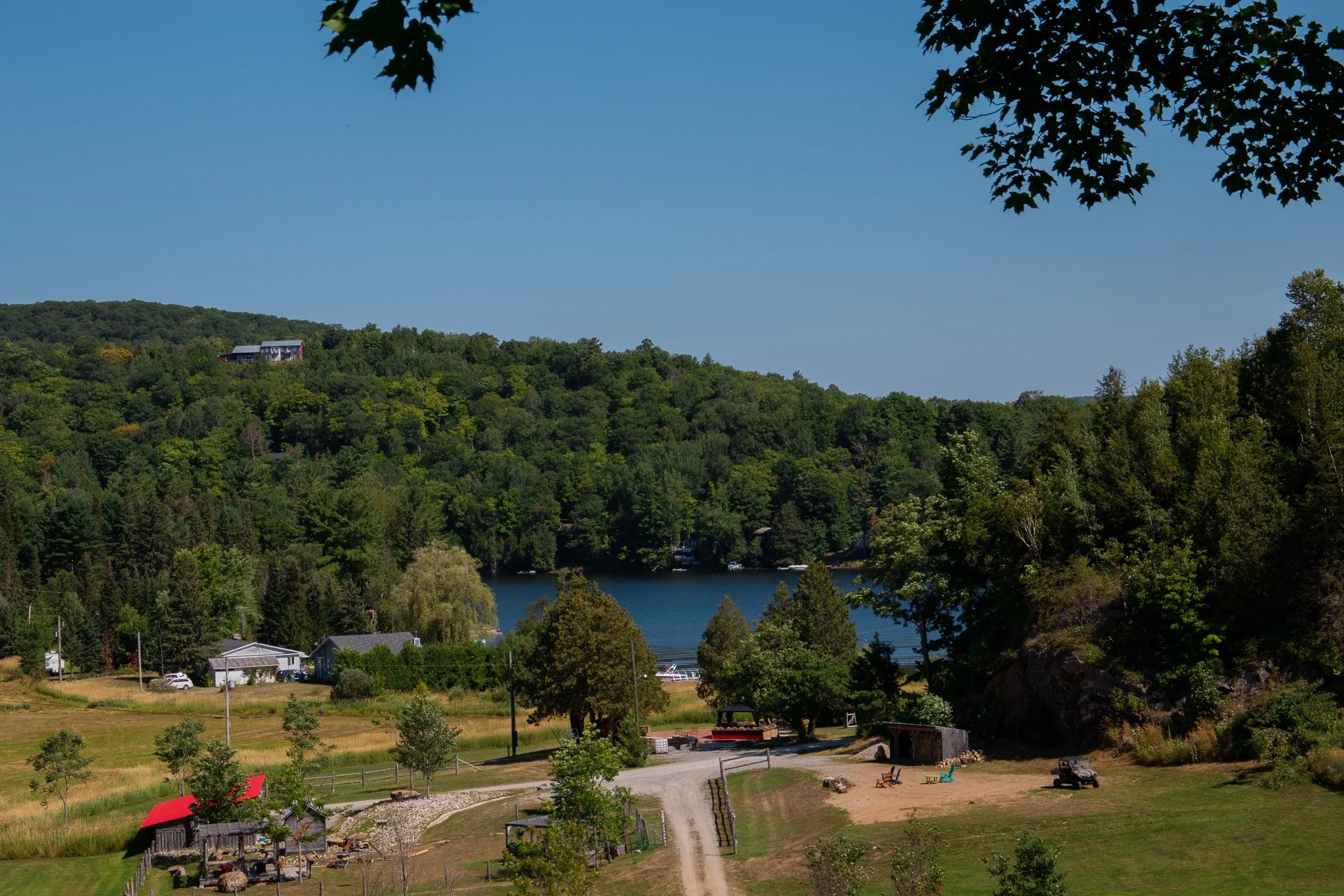 Scenic view of a hilly landscape with a lake, trees, houses, and a clear blue sky.