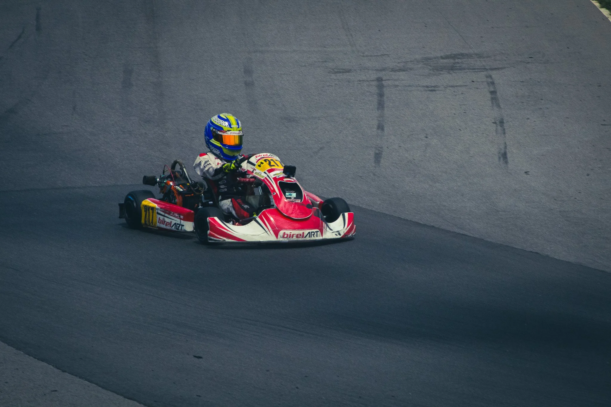 A person in a racing suit and helmet driving a go-kart on a track.