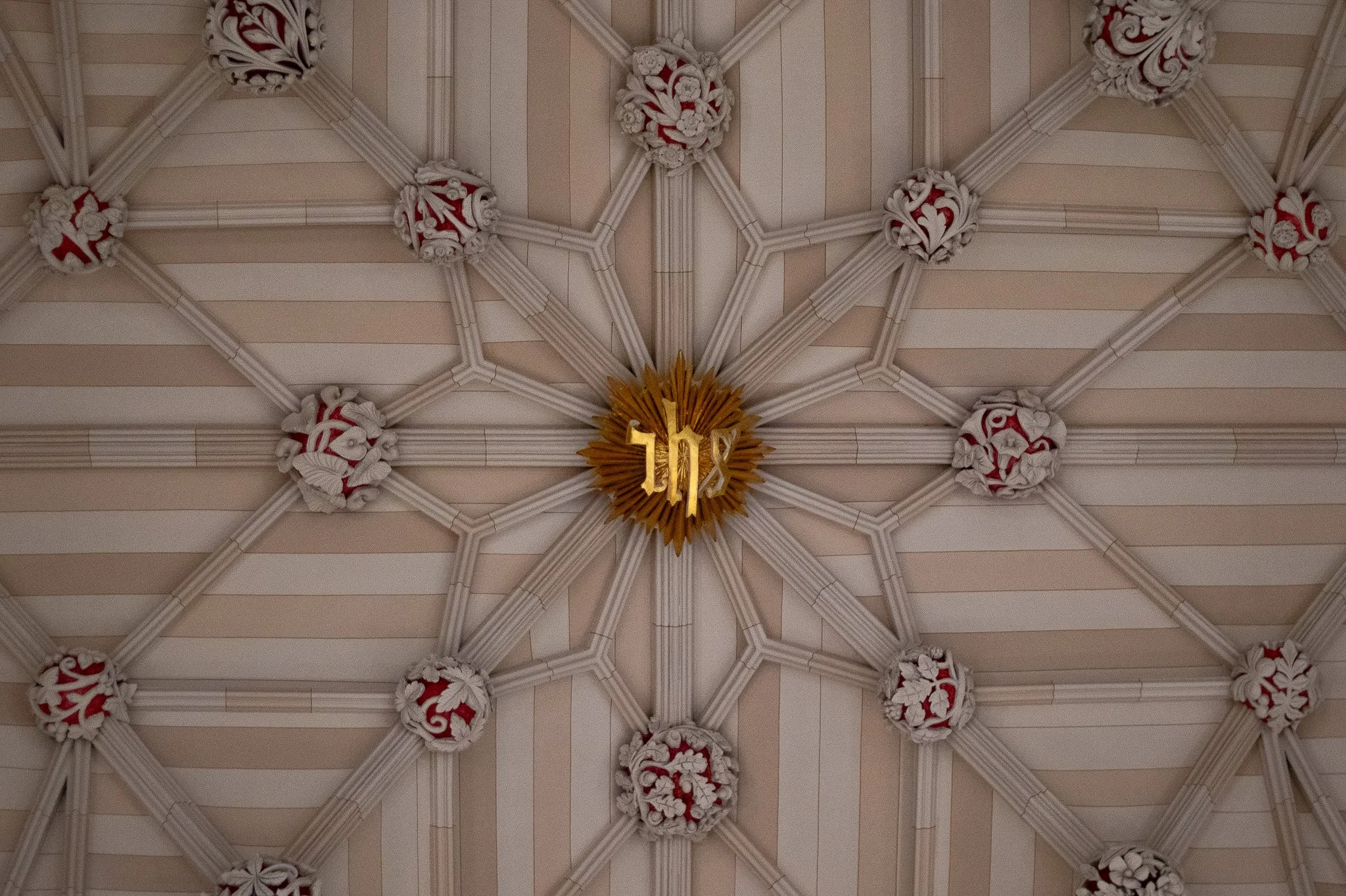 Ceiling with intricate white and red floral design, featuring a golden ornamental element with the number 104 in the center.